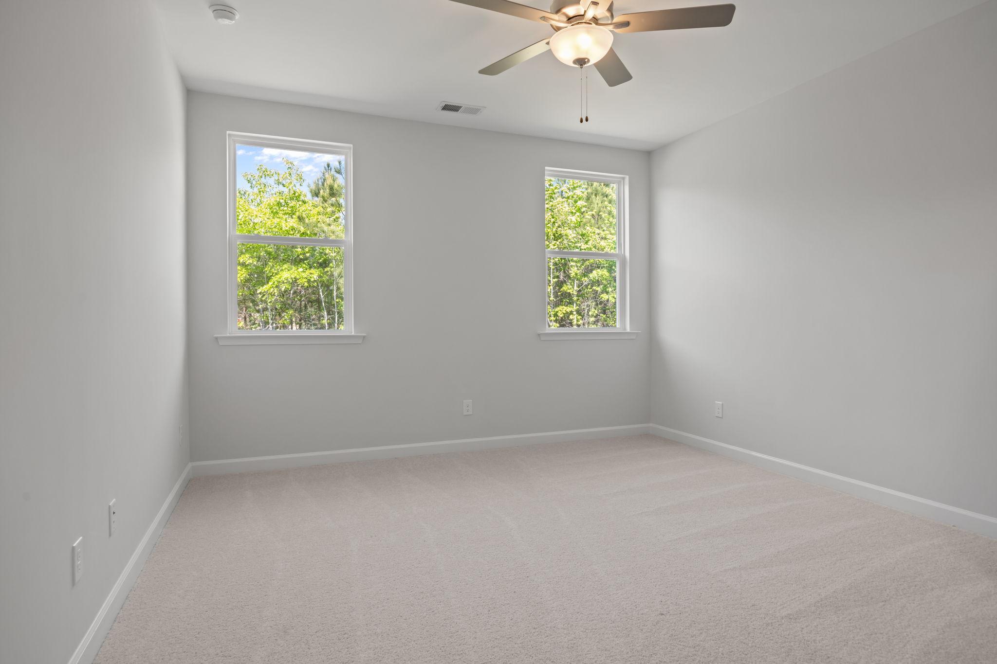 Spacious secondary bedroom in The Ashport B floor plan featuring neutral paint, plush carpeting, and a ceiling fan.