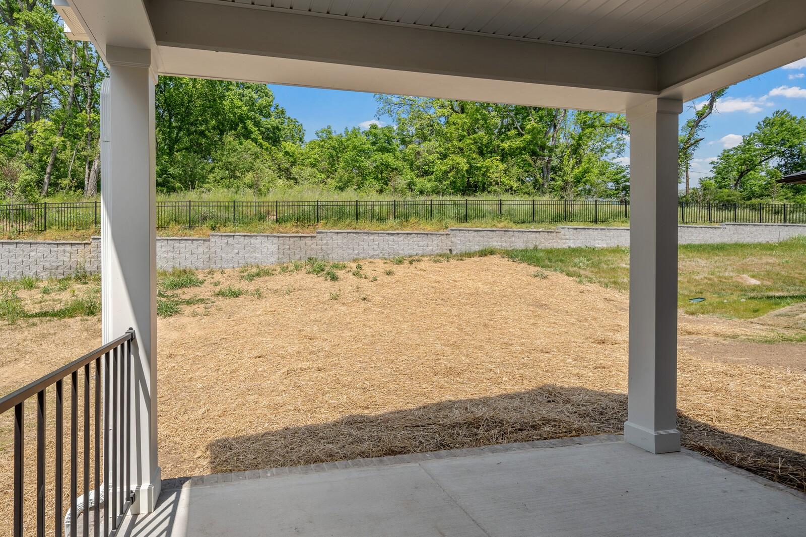 Covered concrete patio overlooking a private backyard with retaining wall at The Willow, Woods Crossing, Gallatin, Tennessee.