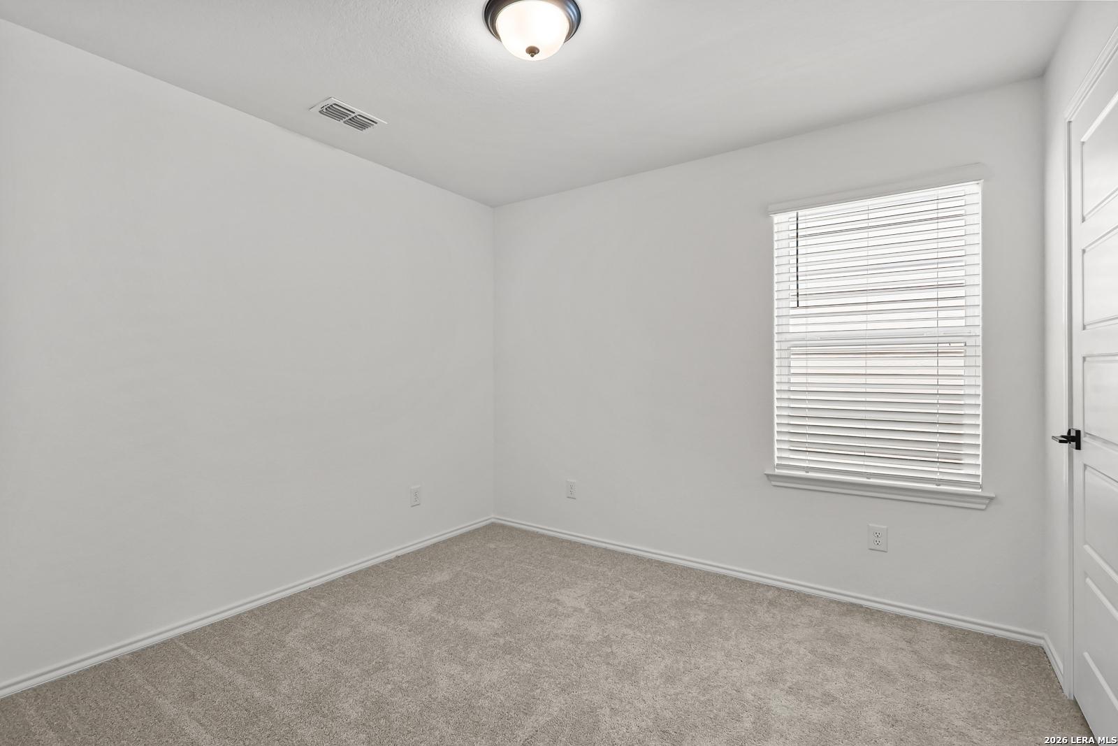 Bright bedroom with carpet and window blinds in The Gillian C floor plan by Davidson Homes in San Antonio, Texas.