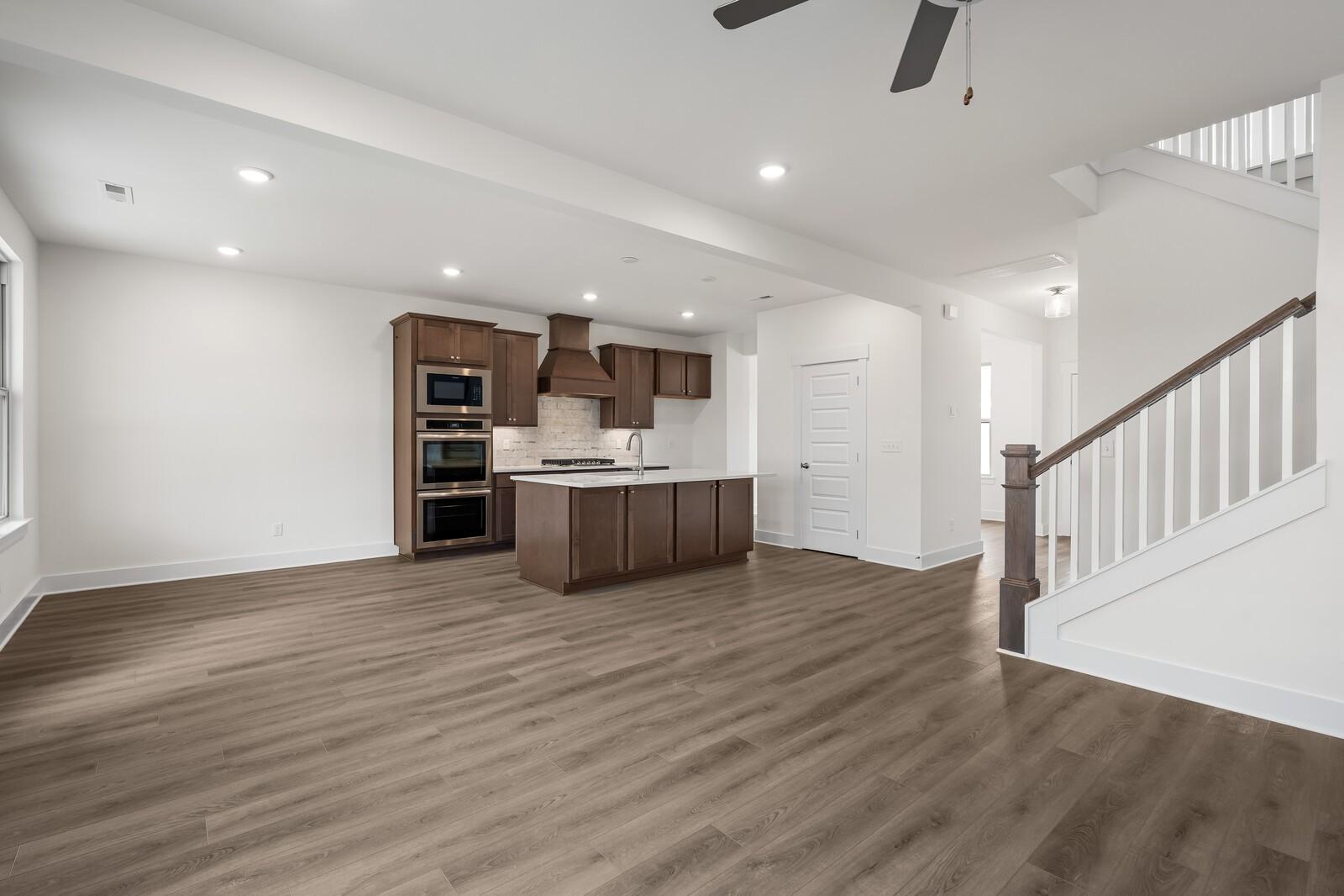 Open-concept kitchen featuring wood cabinets, large island, double oven, and hardwood floors in The Willow C by Davidson Homes, Gallatin, TN