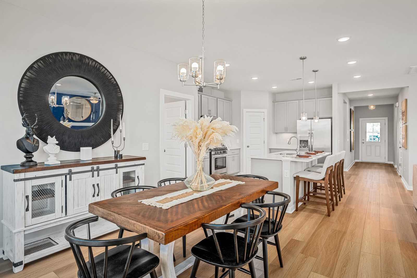 Farmhouse dining room at Sage Farms in White House TN with wooden table, large mirror, pampas grass, and open kitchen