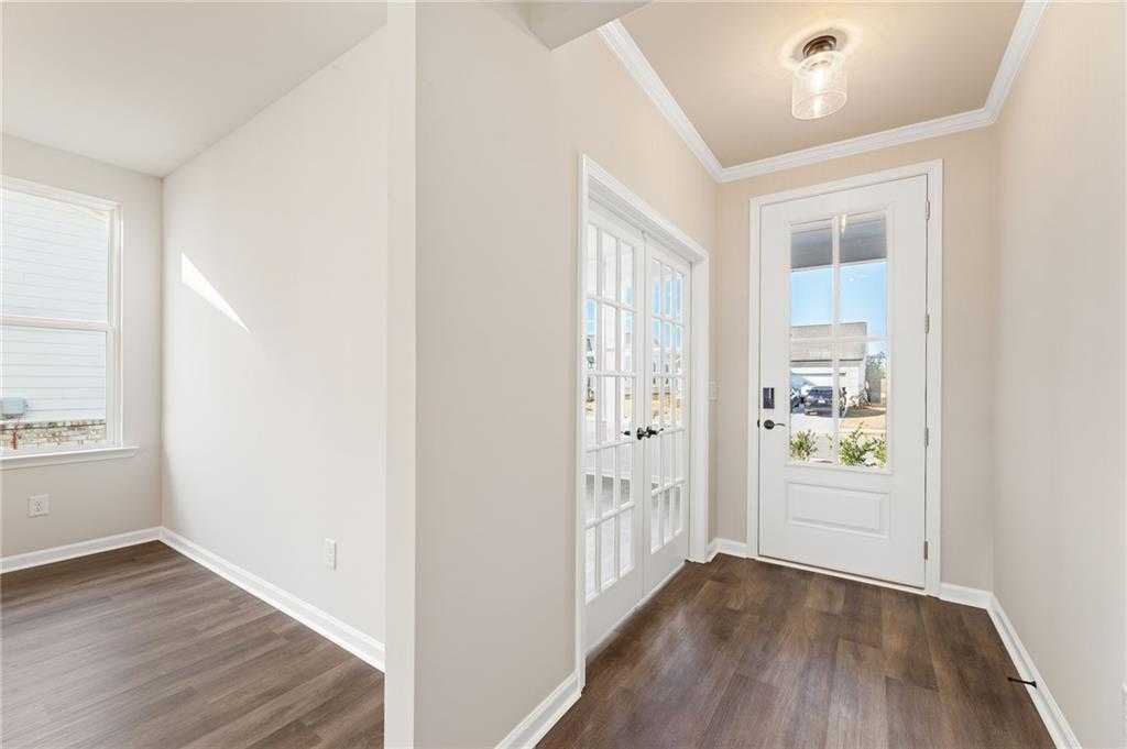 Bright entry foyer with beige walls, hardwood floors, and glass double doors in The Glenwood A by Davidson Homes, Loganville, GA