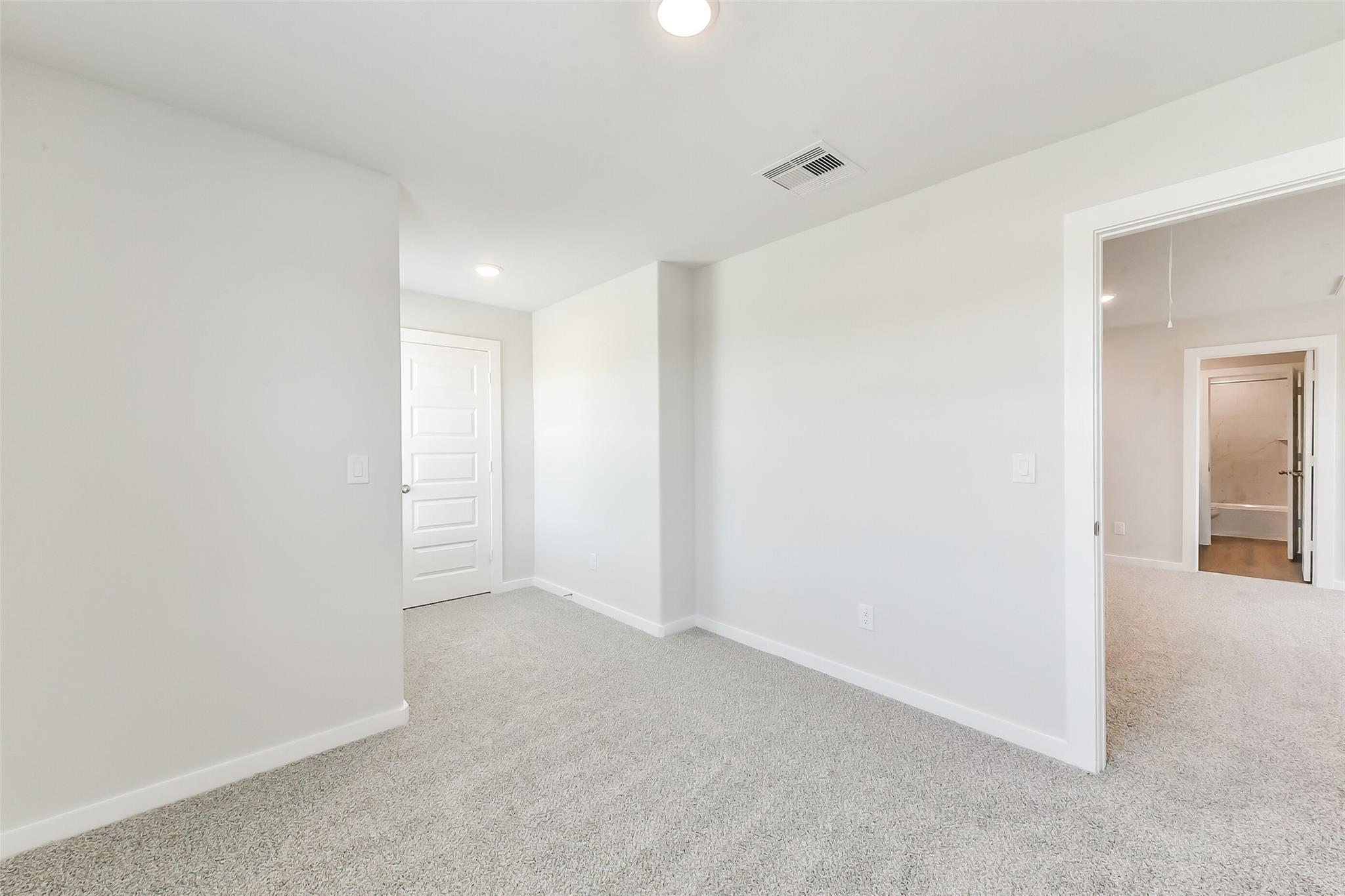 Bright upstairs hallway with gray carpet, white walls, and recessed lighting in Davidson Homes The Brazos E, Magnolia Texas