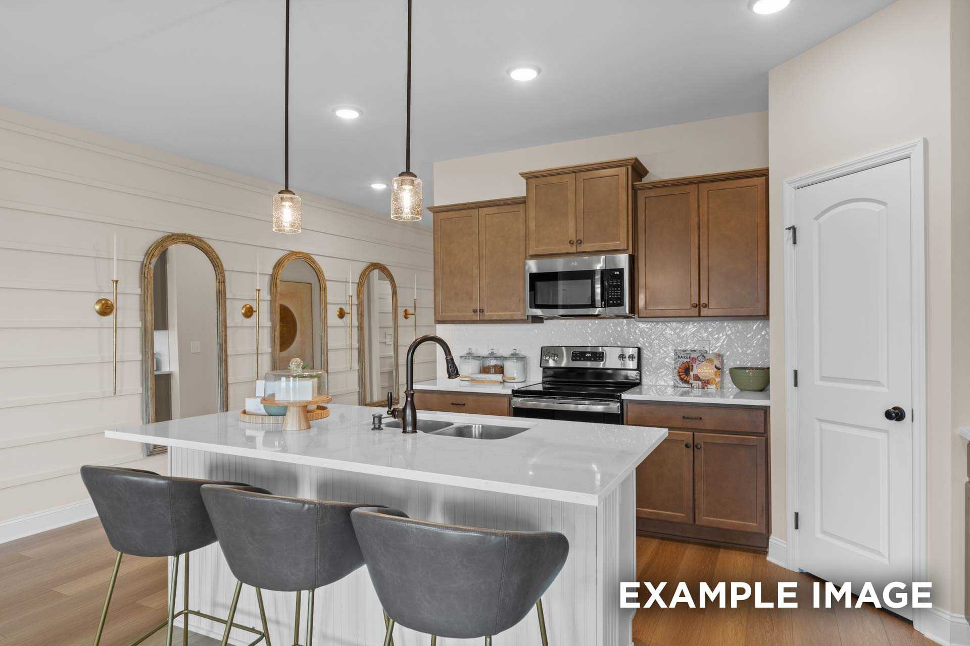 Modern kitchen in The Laurel N by Davidson Homes with white island, shaker cabinets, stainless appliances, pendant lights