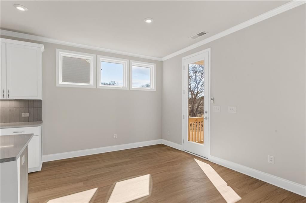 Bright breakfast nook with white cabinets, hardwood floors, and glass door to deck in Davidson Homes The Willow B, Hoschton, GA