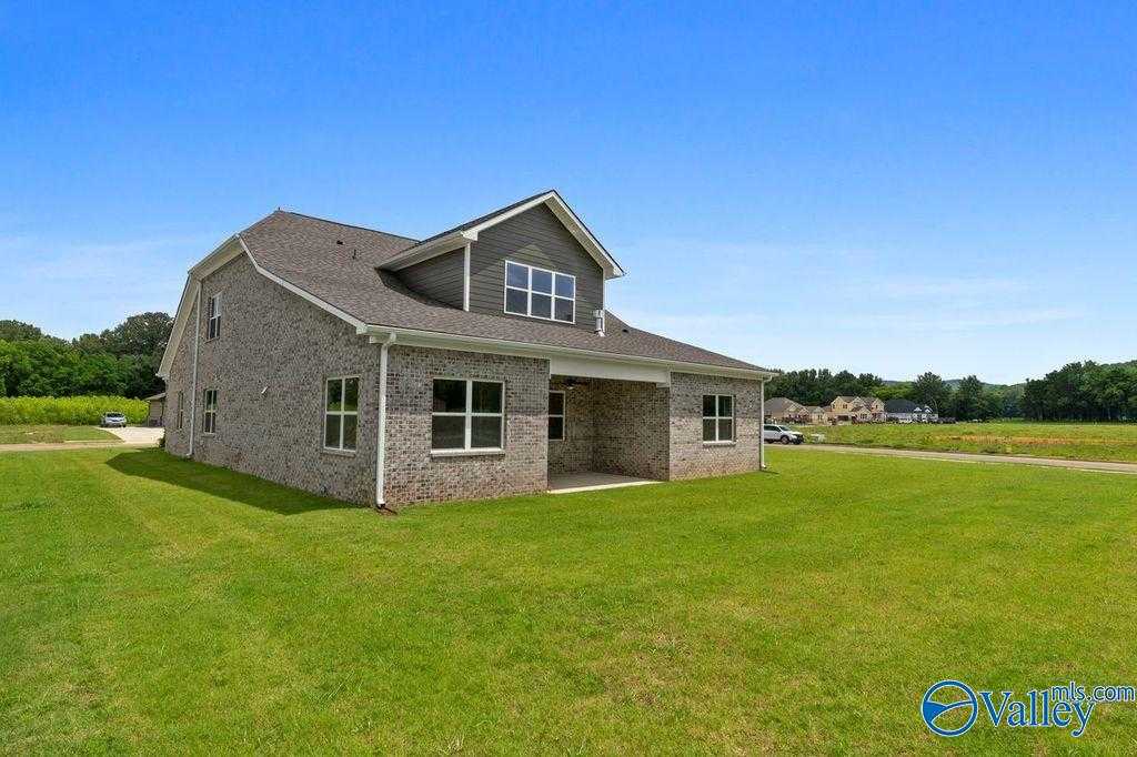 Modern 1.5-story gray brick home with gabled roof, covered porch, and expansive green lawn in The Meadows at Hampton Cove, Owens Cross Roads, Alabama