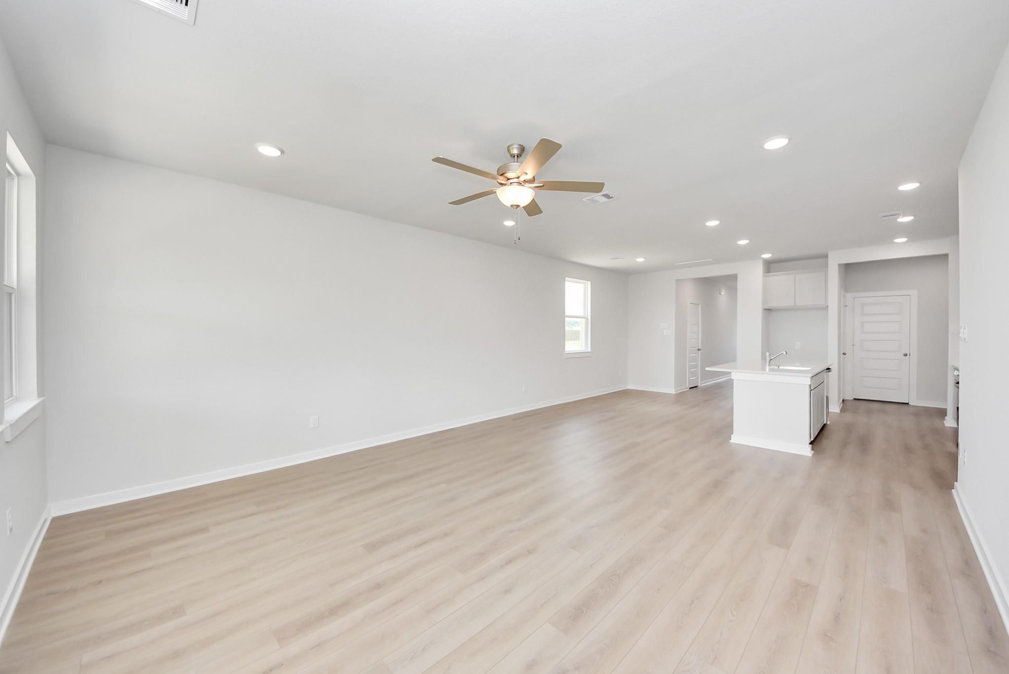 Open-concept living room with light wood floors in The Blanco F floor plan at Spring Branch Crossing, Conroe, Texas.