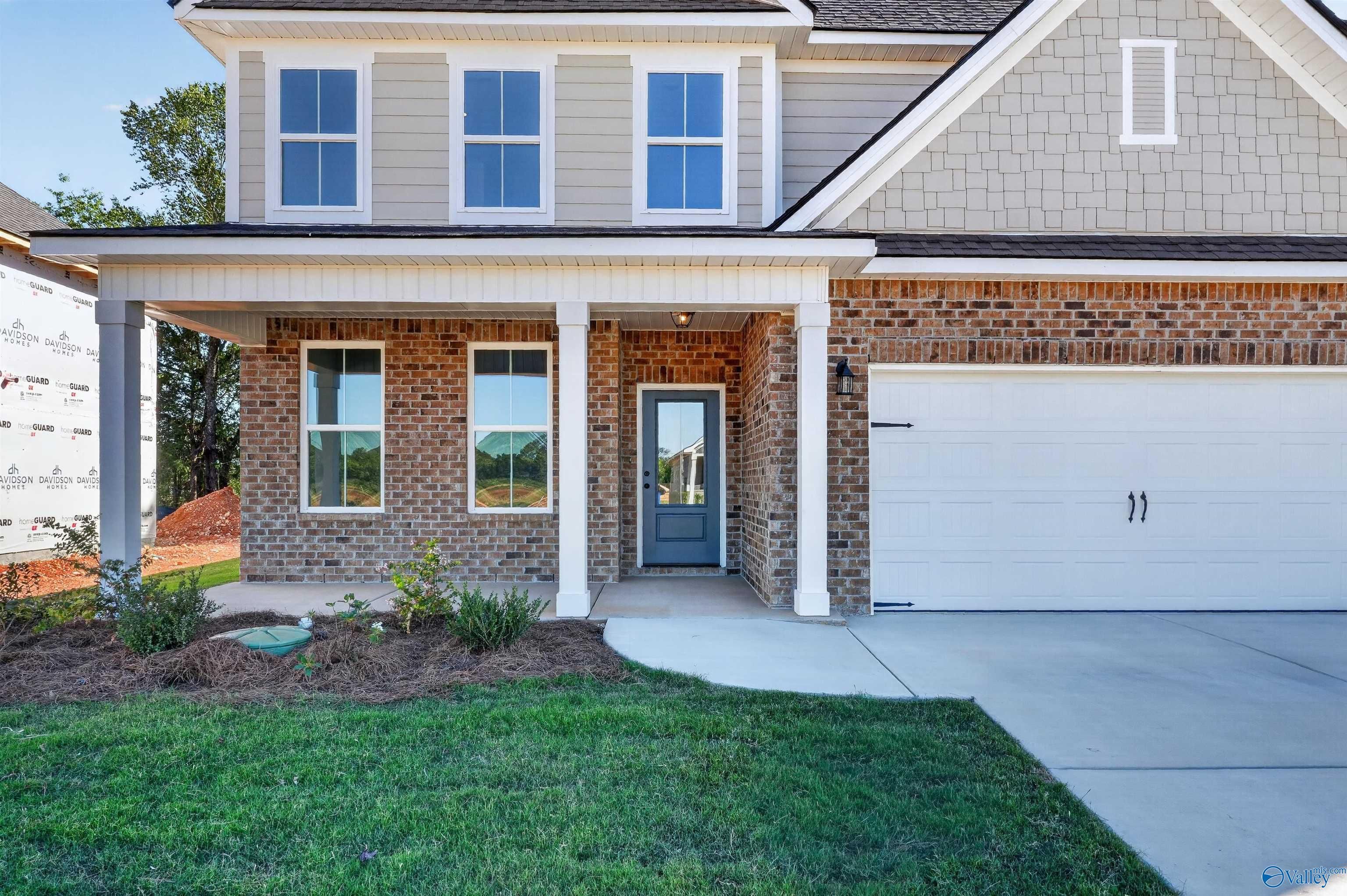 Brick and siding exterior with covered front porch and 2-car garage at The Ashport L by Davidson Homes in Berry Cove, Alabama