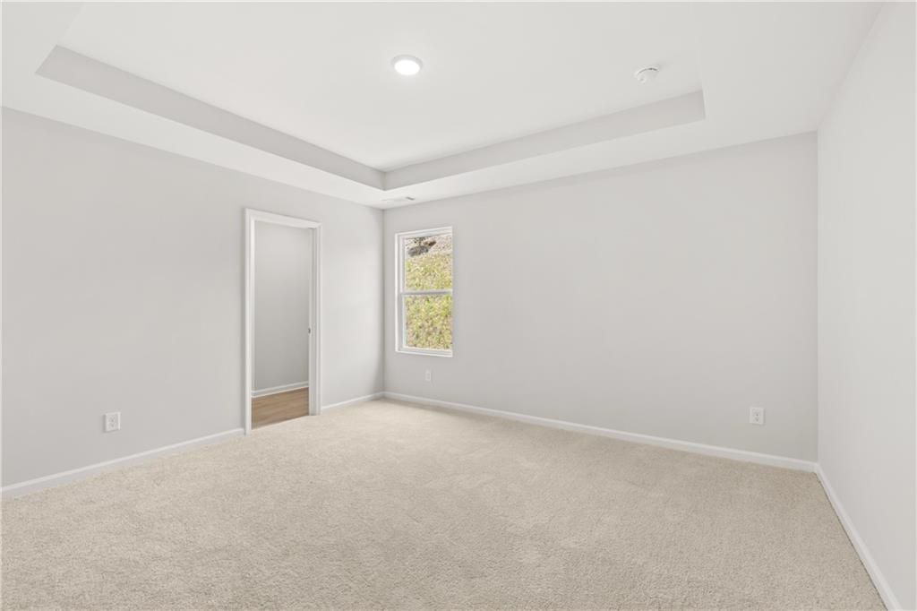 Bright bedroom with a tray ceiling in The Burton A floor plan at The Bluffs in Canton, Georgia by Davidson Homes.