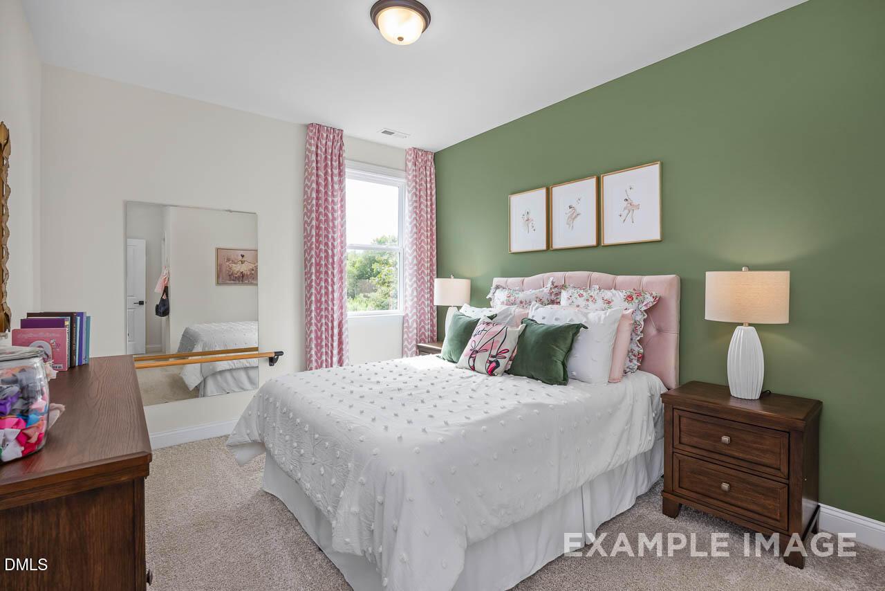 Cozy bedroom with green accent wall and pink headboard in The Crawford D floor plan, Rockport, Wake Forest, NC.