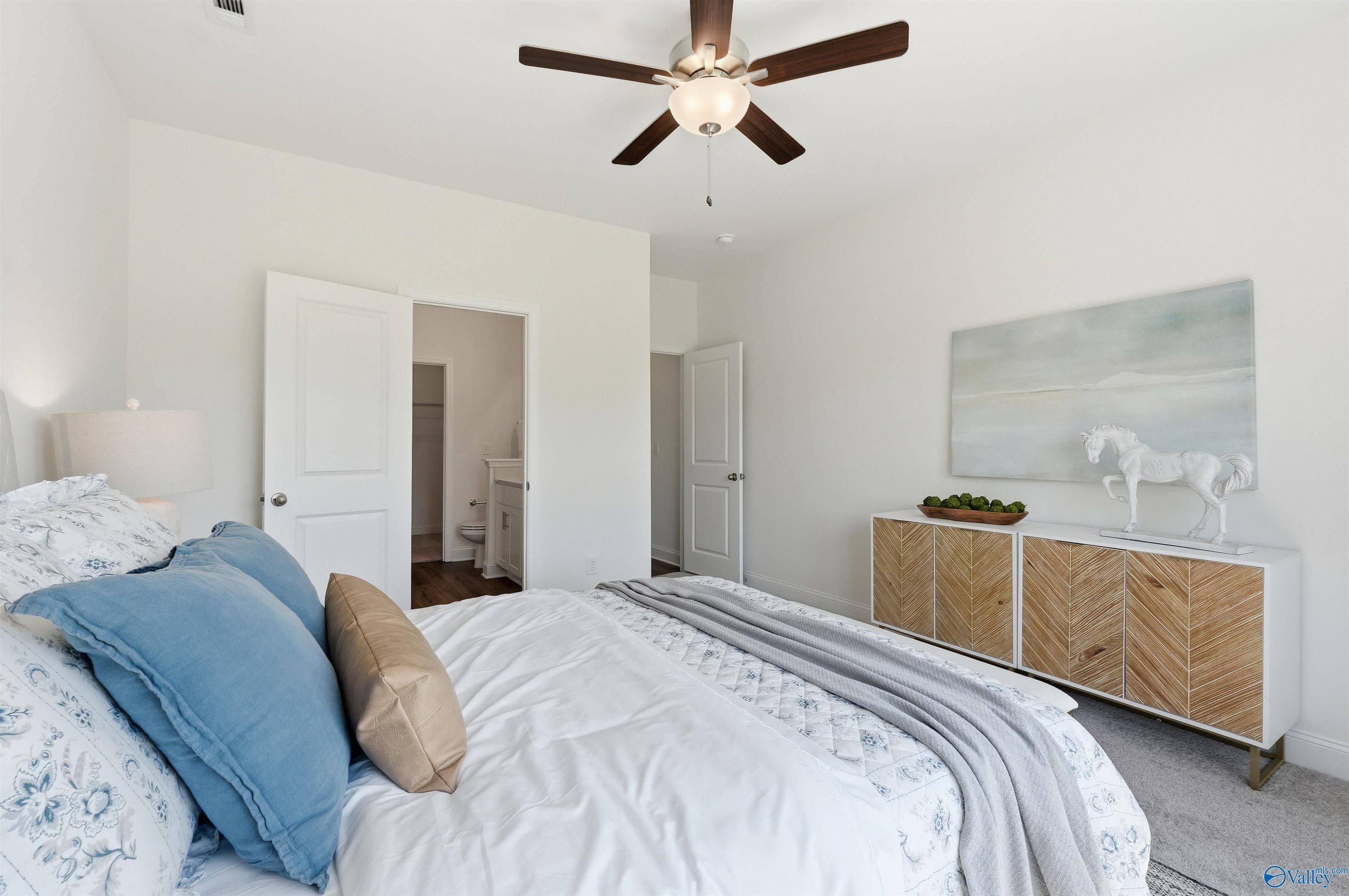 Bright bedroom with ceiling fan and en-suite bathroom in The Franklin C floor plan at Lynn Meadows, Meridianville, Alabama.