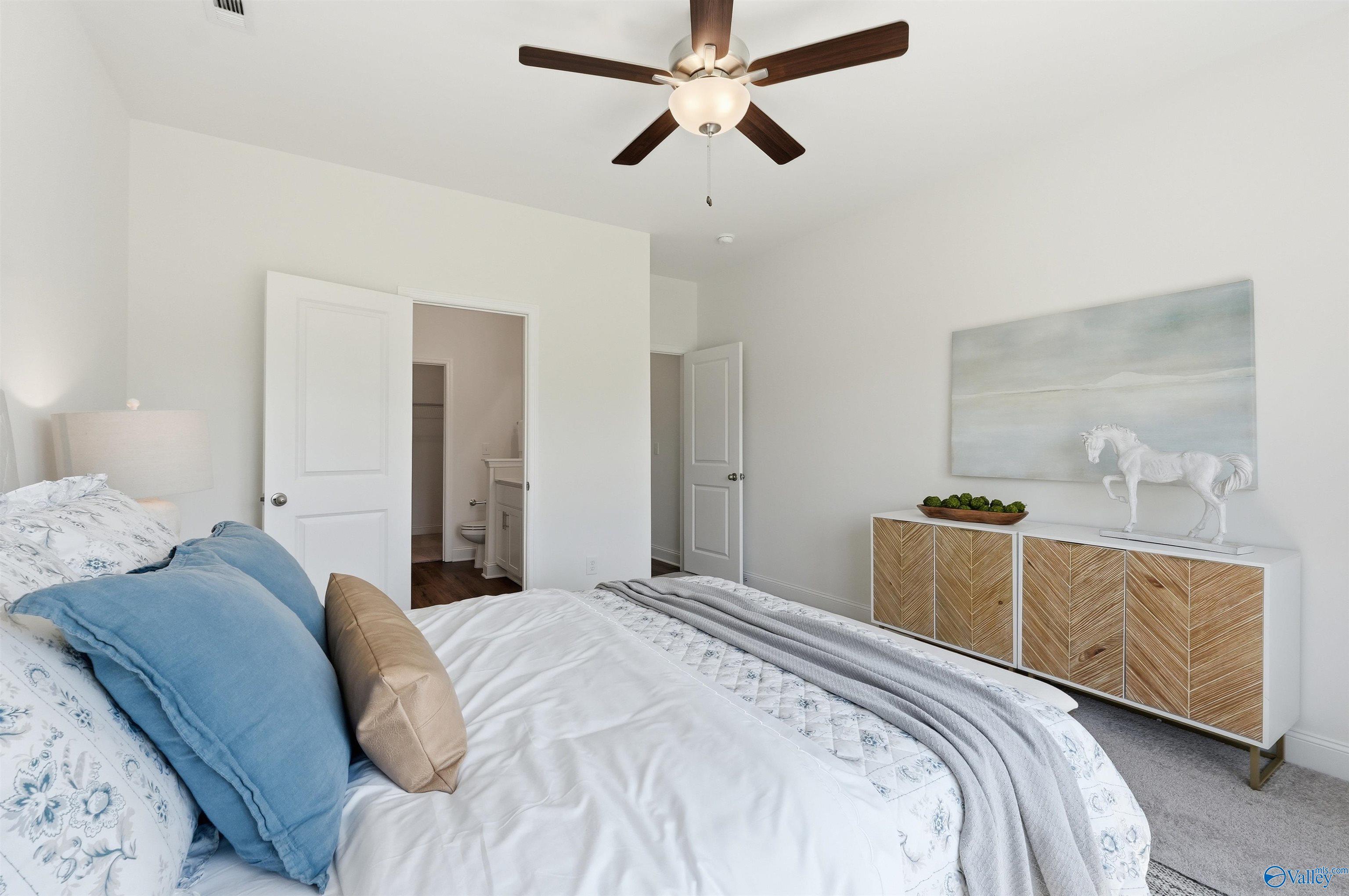 Bright bedroom with ceiling fan and en-suite bathroom in The Franklin C floor plan at Lynn Meadows, Meridianville, Alabama.