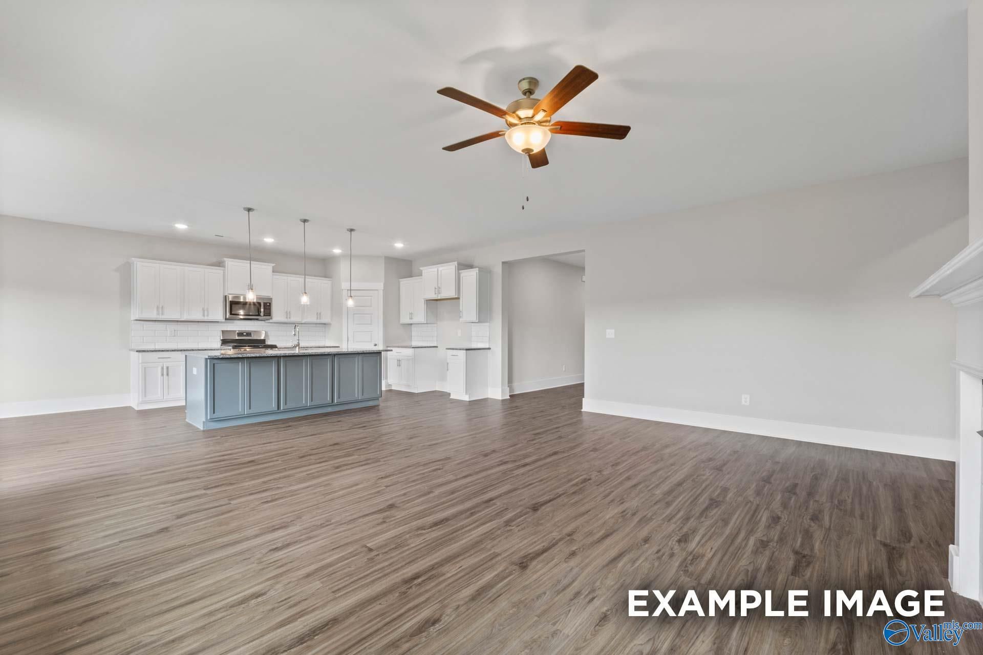 Open-concept kitchen with blue island, white cabinets, hardwood floors, and ceiling fan in Davidson Homes The Harrison, Hartselle, AL