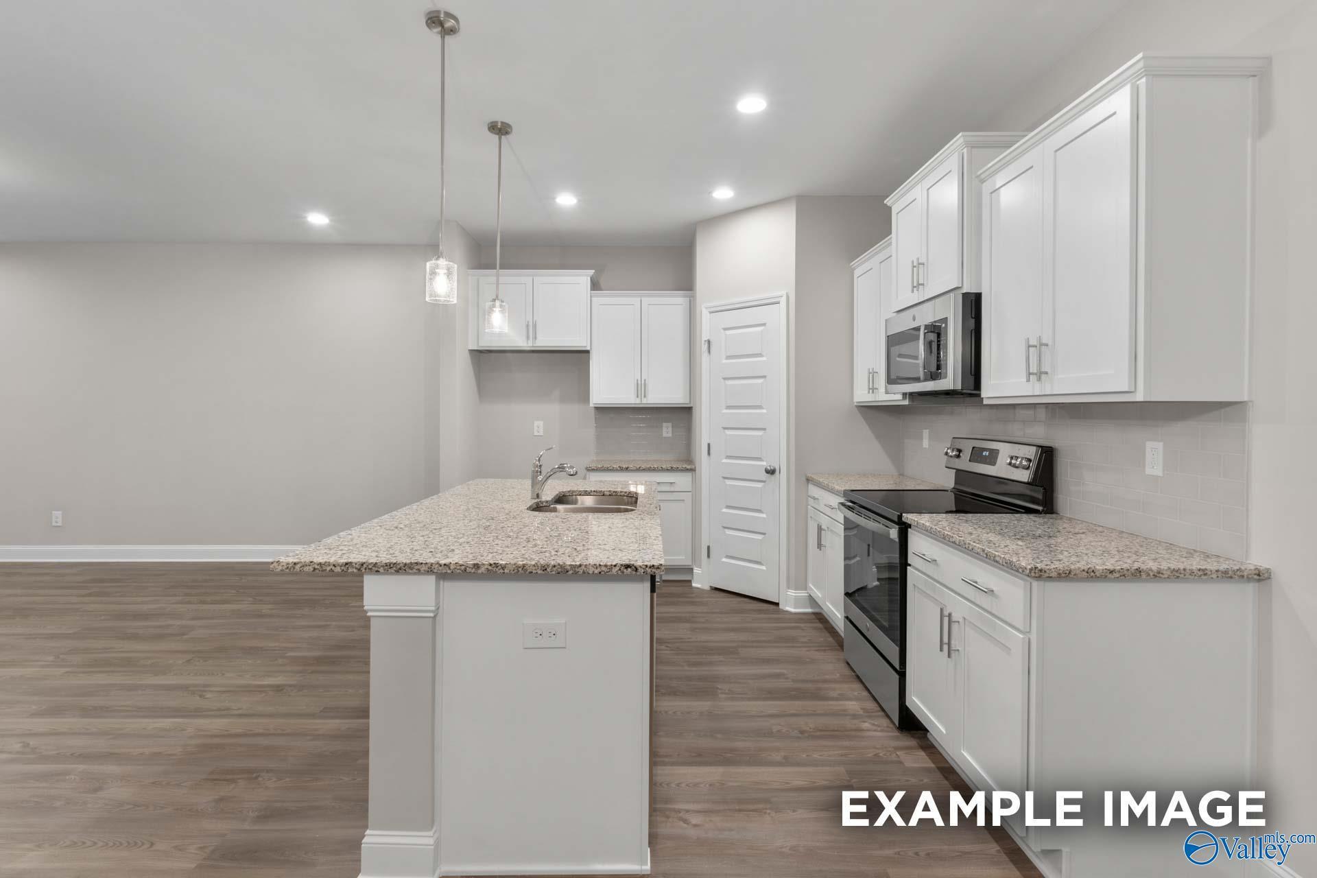 Modern kitchen featuring white shaker cabinets, granite island sink, stainless steel appliances in The Camilla C by Davidson Homes