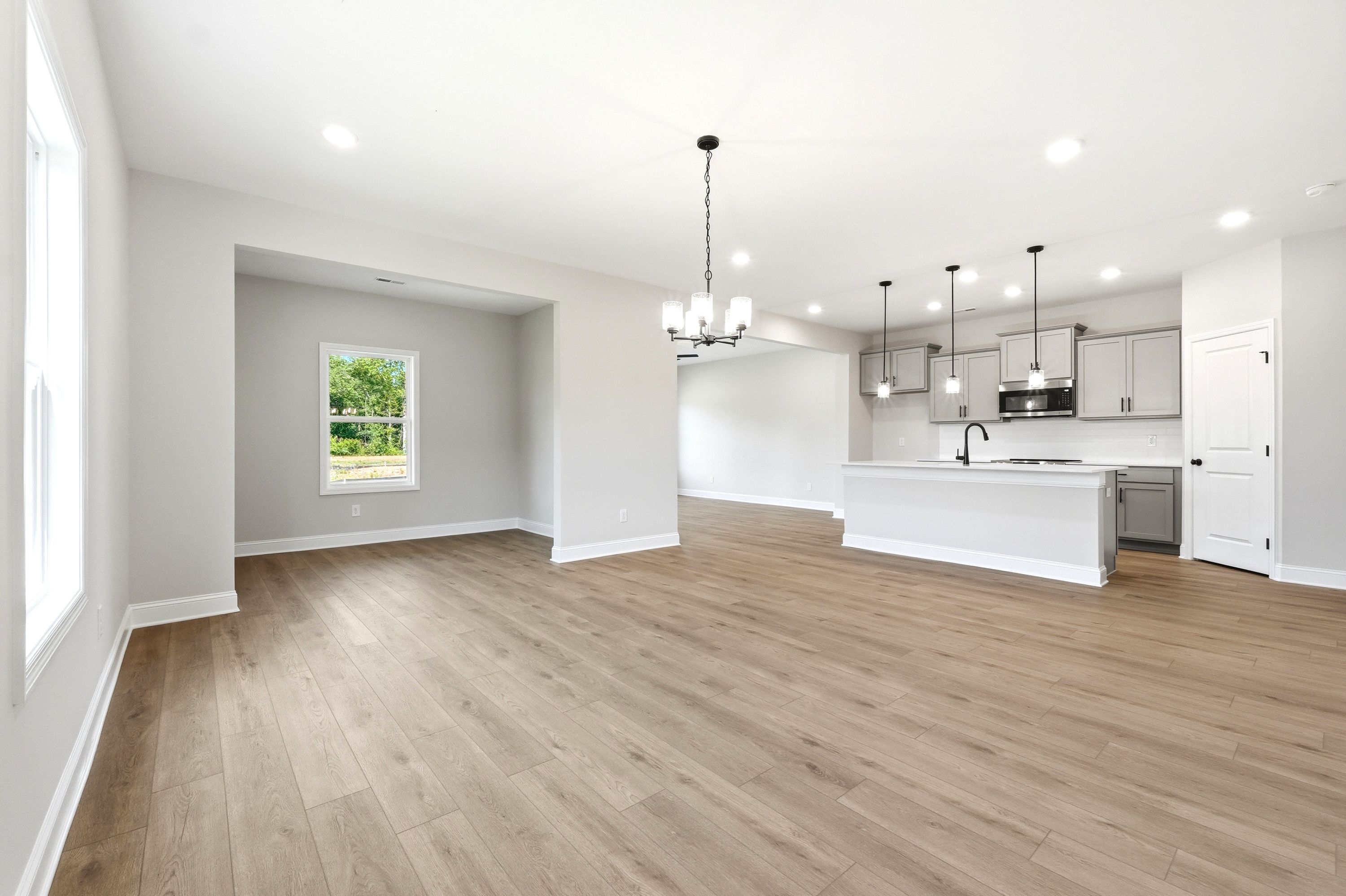 Open-concept living and dining area in The Russell A by Davidson Homes featuring luxury vinyl plank flooring and kitchen.
