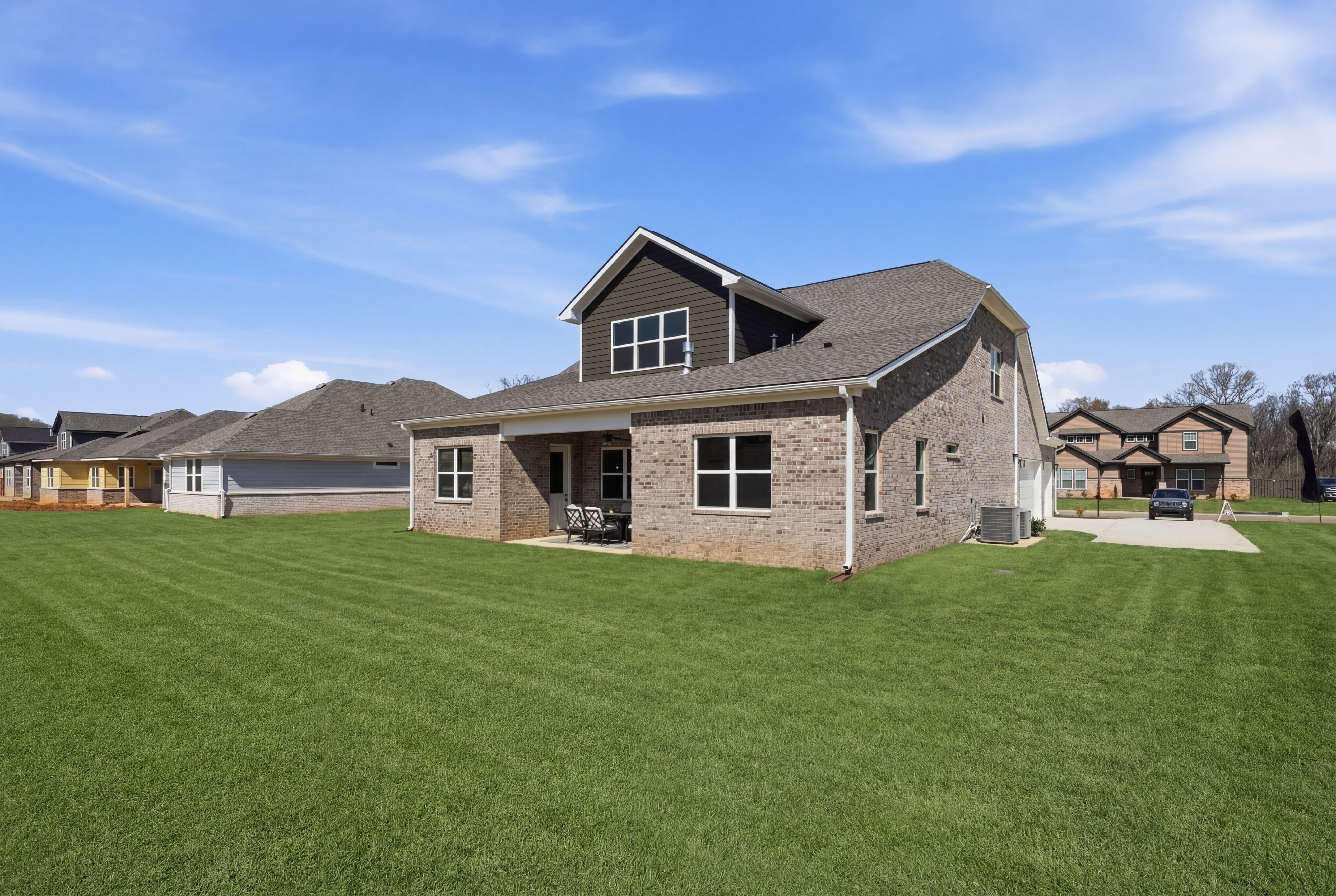 Brick ranch home exterior with covered porch, garage and lush lawn at The Meadows at Hampton Cove in Owens Cross Roads, Alabama