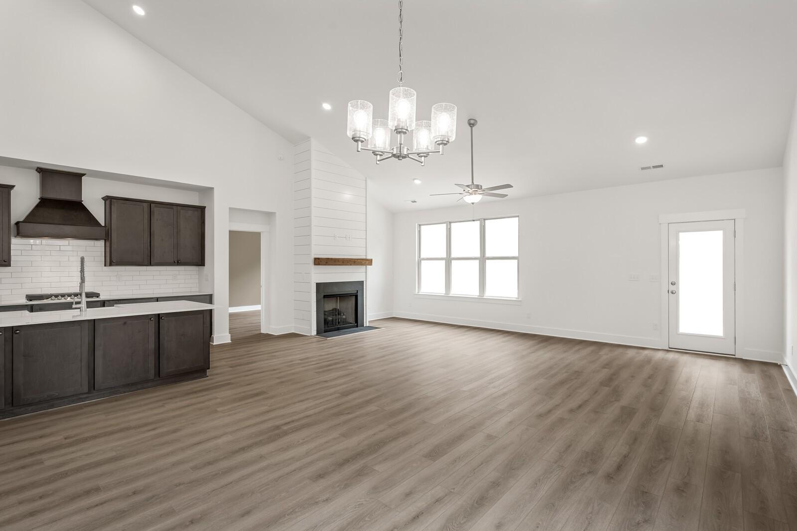 Open-concept living room with fireplace and modern kitchen in The Ridgeport C floor plan at Woods Crossing, Gallatin, TN.