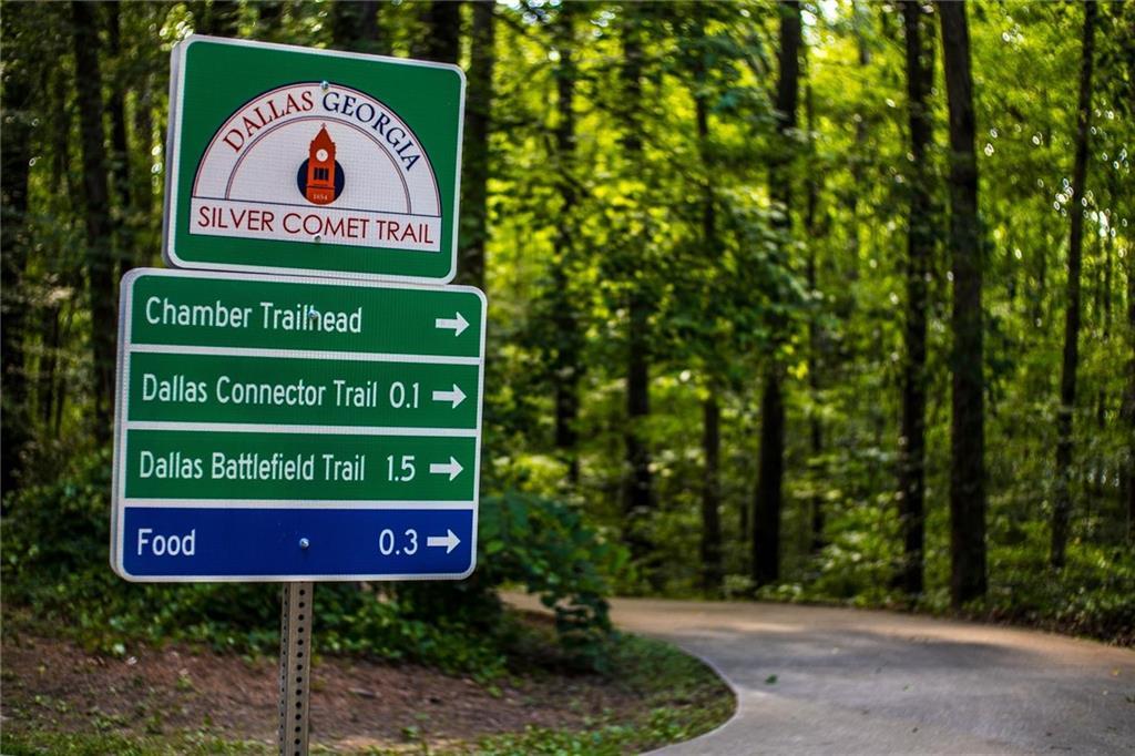 Green Silver Comet Trail signs in Dallas, Georgia, directing to Chamber Trailhead 0.1 mi, Dallas Connector 0.1 mi, Battlefield 1.5 mi, food 0.3 mi along wooded path
