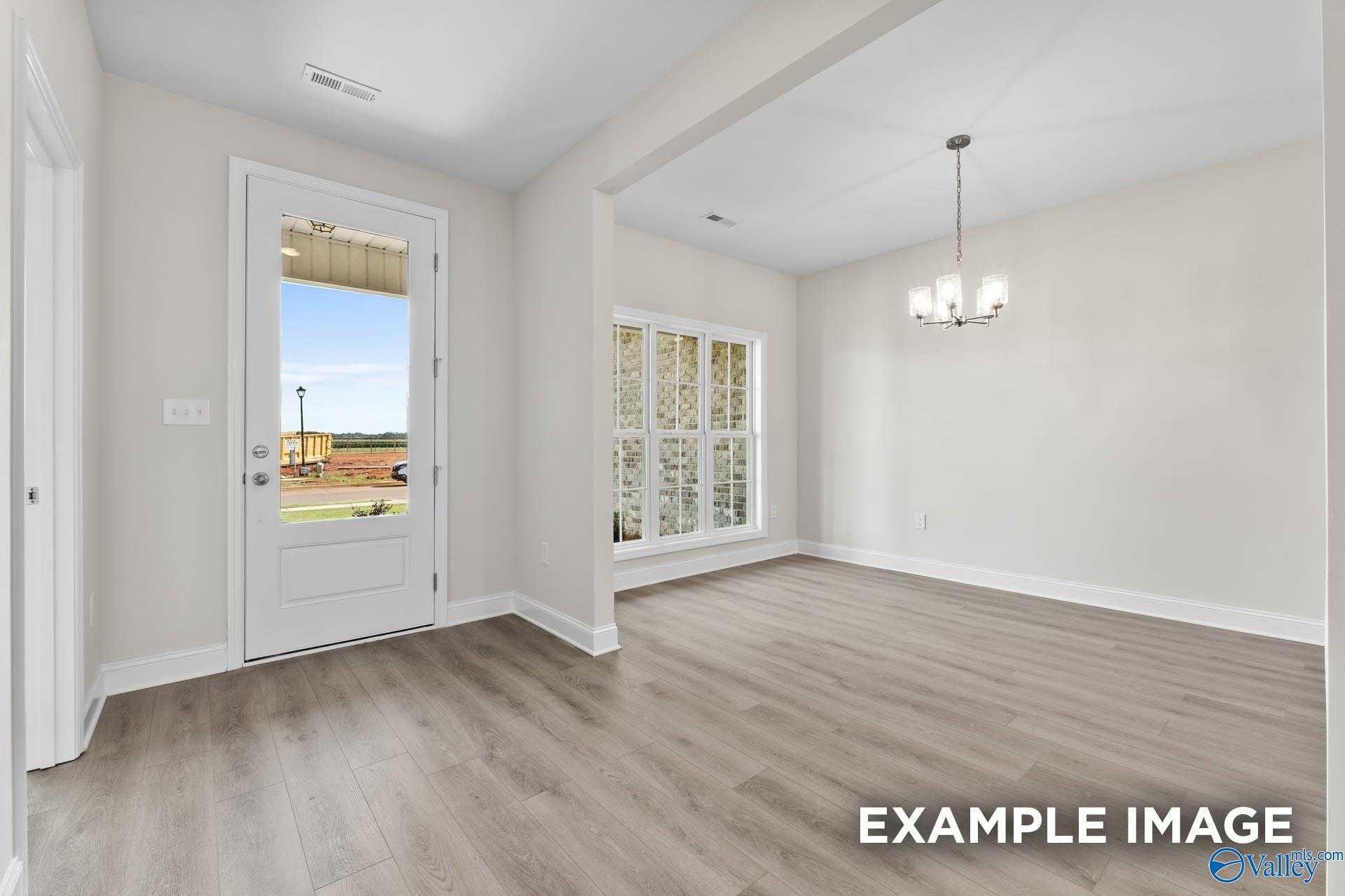 Bright entryway with open French door to sunny patio, large grid windows, and chandelier in Davidson Homes The Finleigh, Meridianville