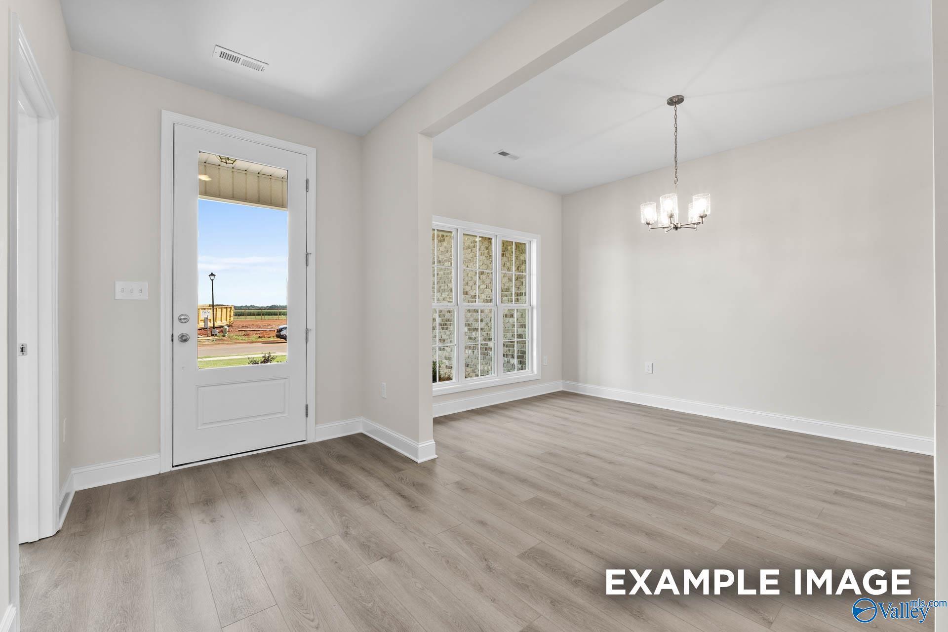 Spacious entryway with hardwood floors, chandelier, and backyard view through large windows in The Finleigh home, Huntsville AL