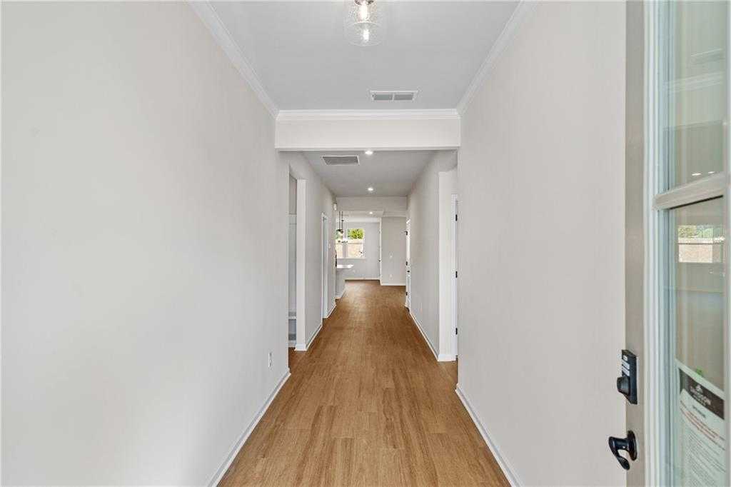 Bright hallway with hardwood floors, white walls, and recessed lights in The Edison A 3-bedroom home, Loganville, Georgia