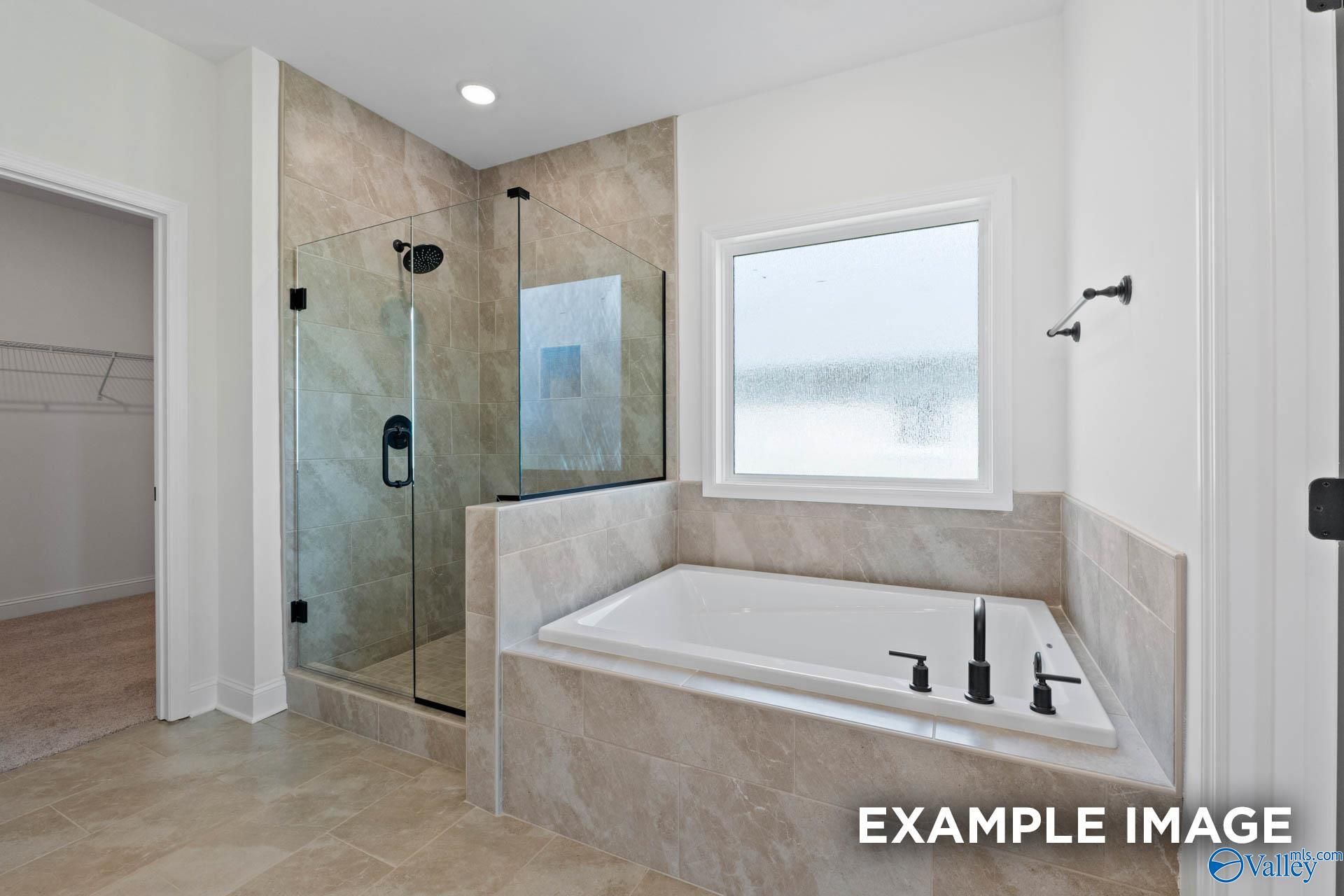 Modern primary bathroom with a tiled walk-in shower and soaking tub in The Rockford B floor plan at Briercreek, Meridianville.