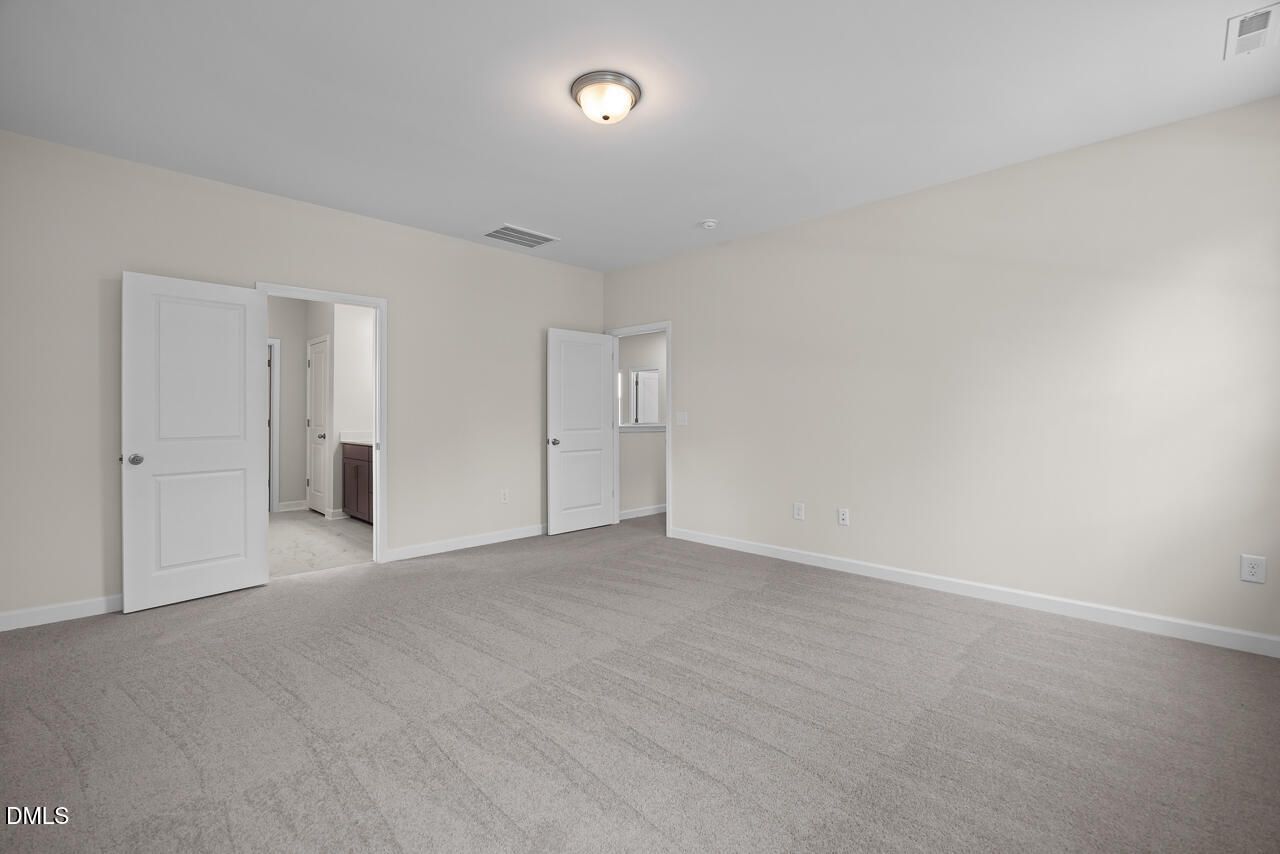 Spacious bedroom with plush carpeting and ensuite bathroom access in The Hickory II B plan at Montrose, Aberdeen, NC.
