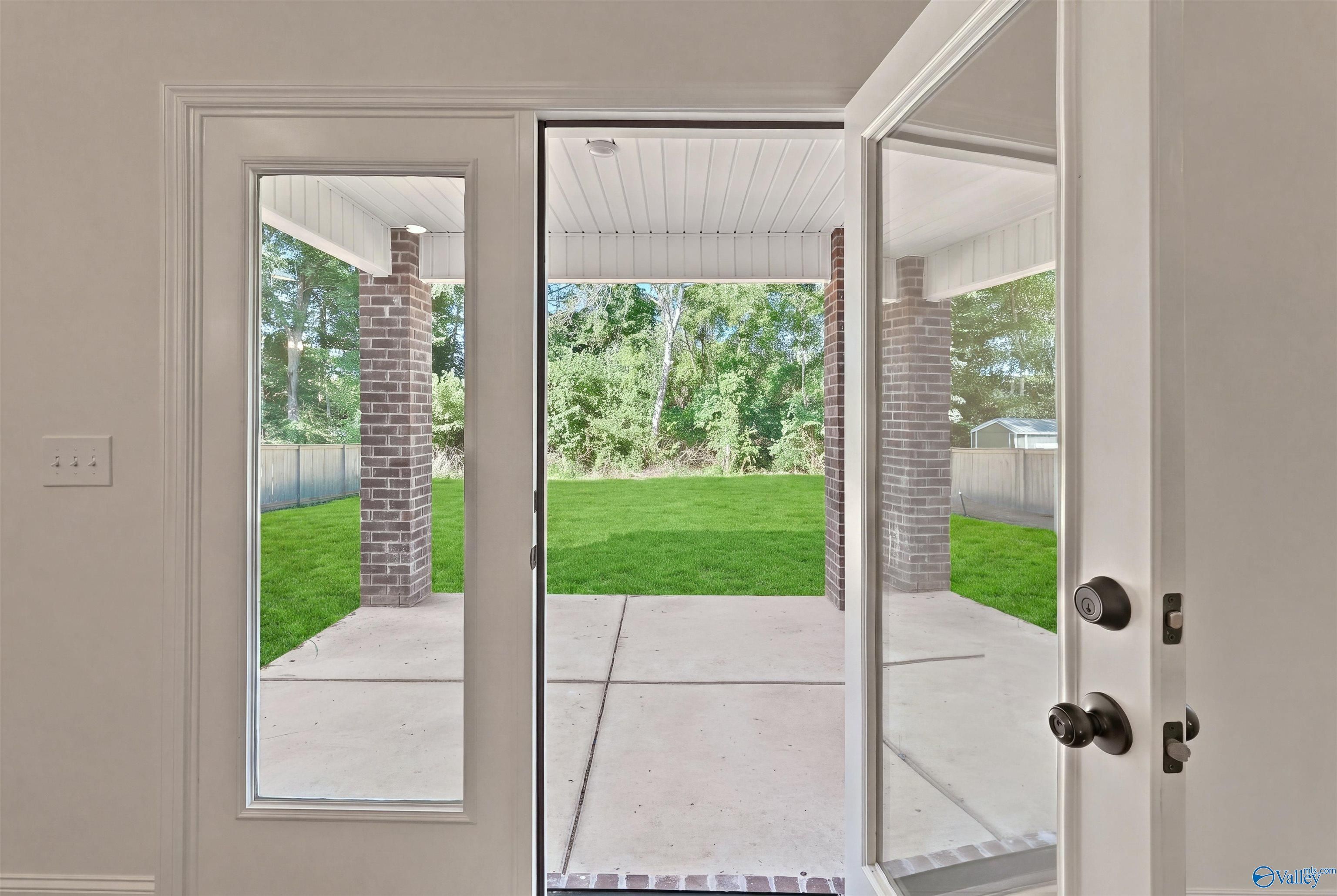 View of covered back patio and private backyard from glass door of The Chelsea C home in Creek Grove, New Market, Alabama.