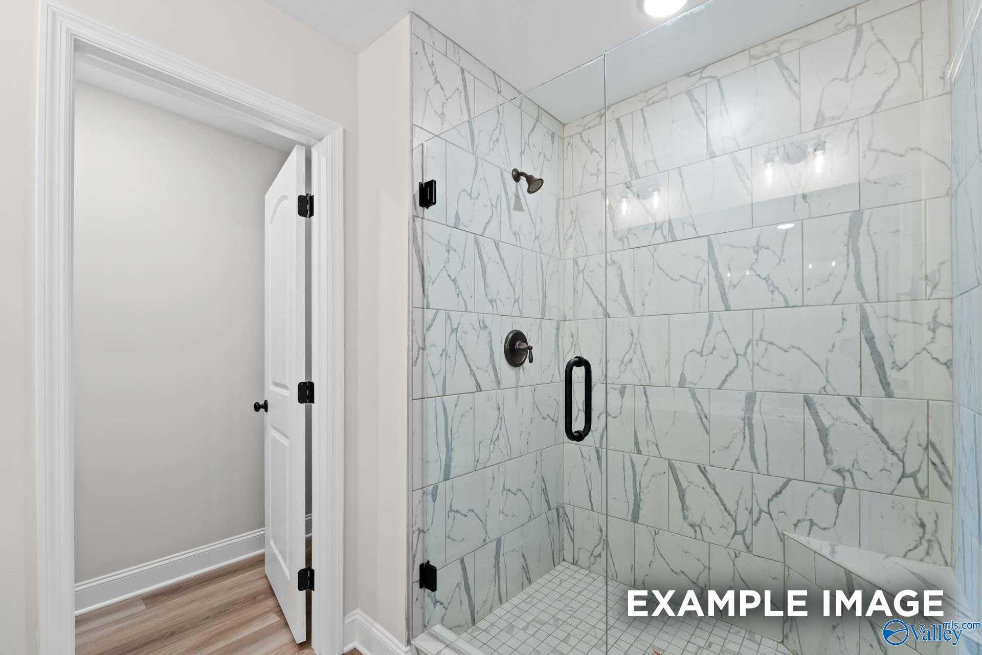 Elegant master bathroom shower with white subway tile, frameless glass door, and rainfall head in Davidson Homes The Camden D, Huntsville