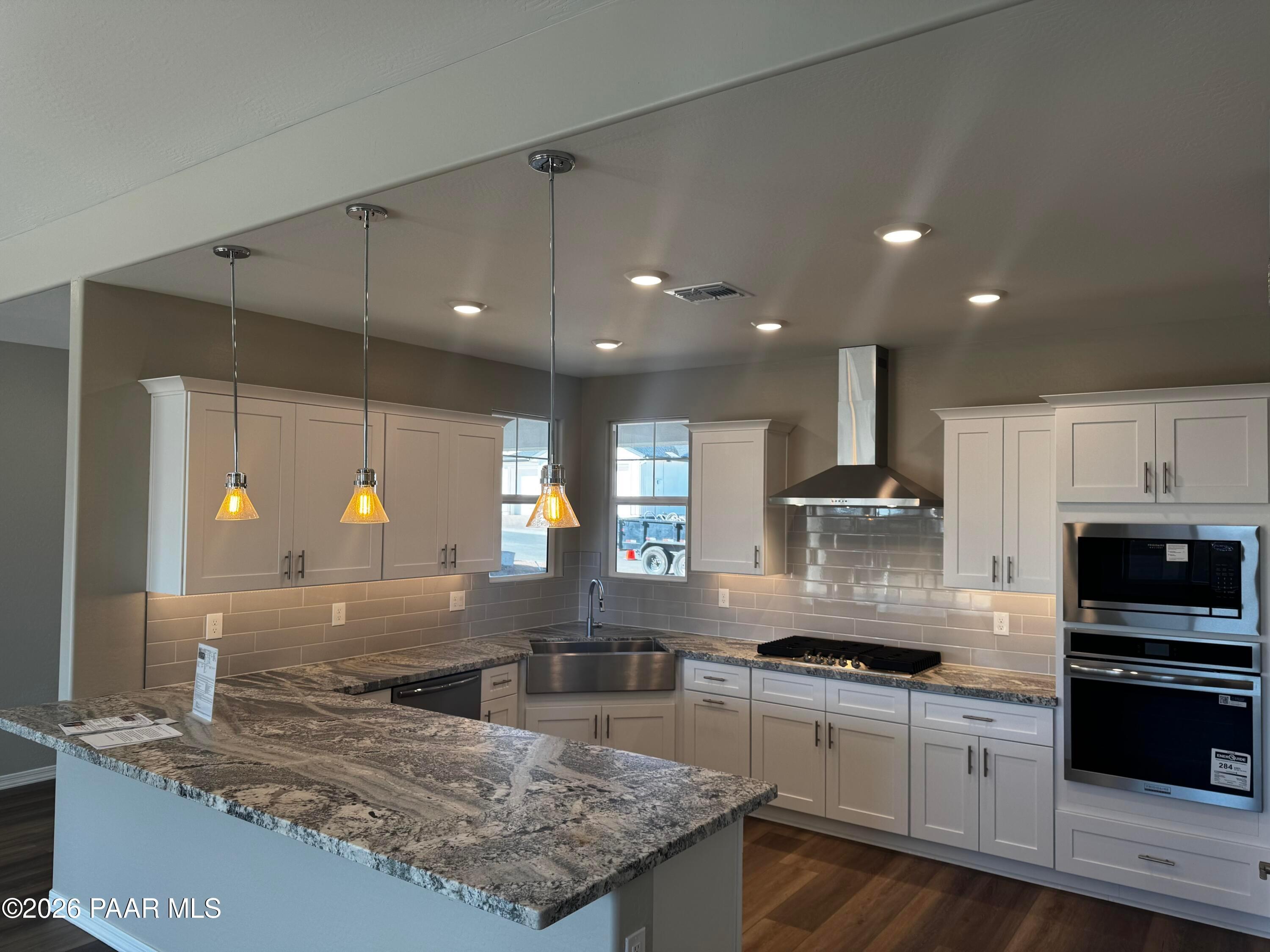Modern white shaker kitchen with granite countertops, stainless appliances, and island in Davidson Homes The Daybreak B, Prescott AZ