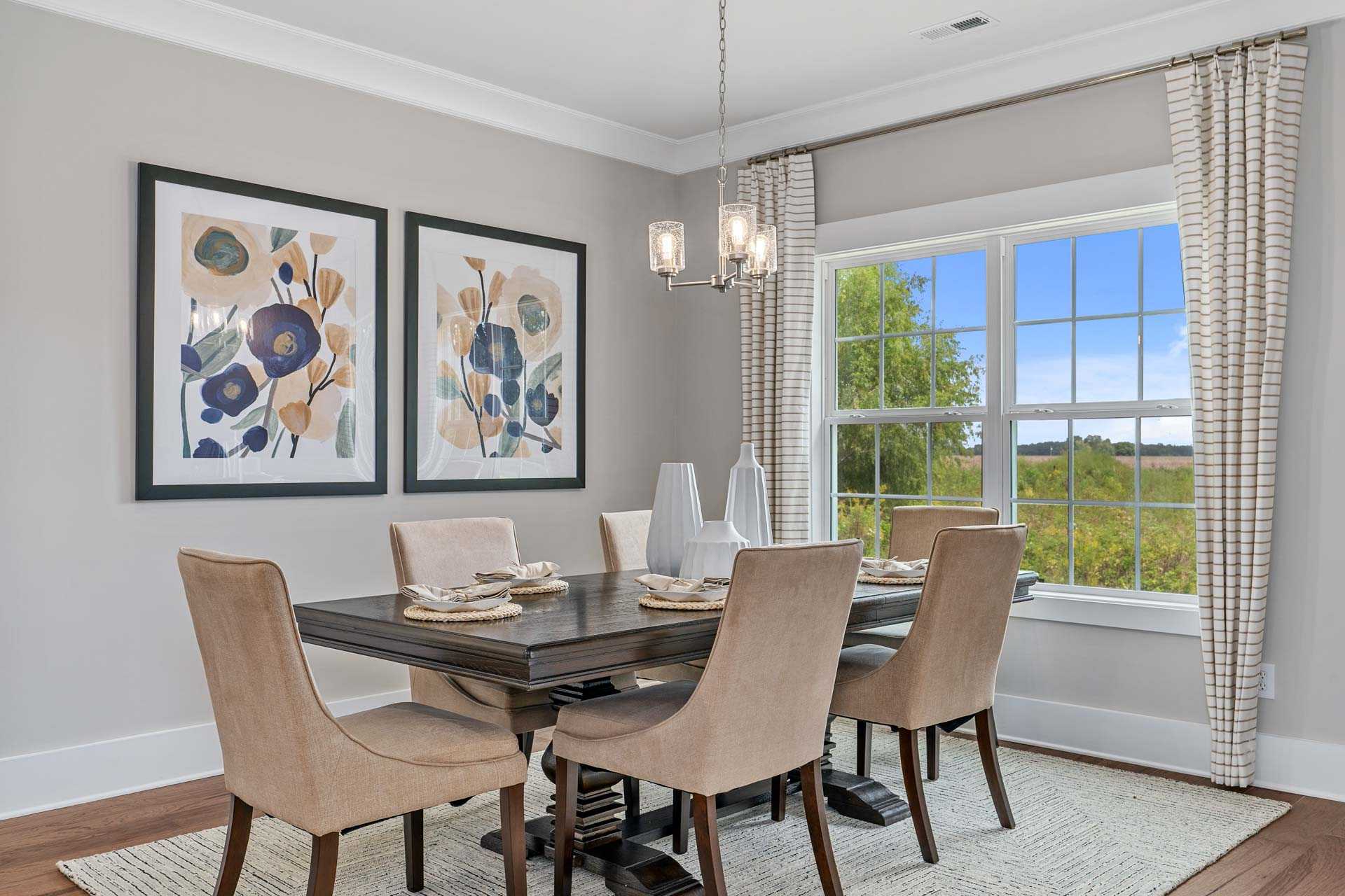 Elegant dining room at Kendall Downs in Toney Alabama with wooden table, upholstered chairs, chandelier, abstract floral art, and scenic window view