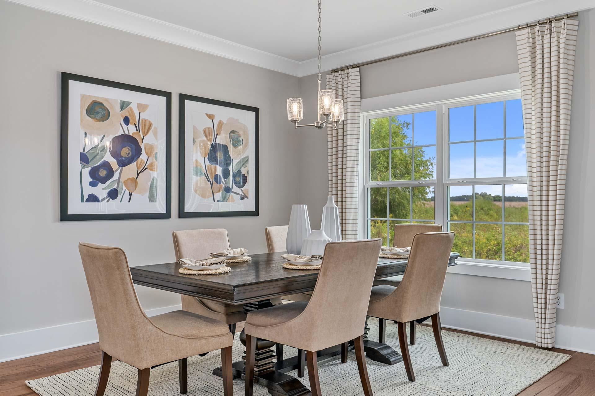 Elegant dining room at Kendall Downs in Toney Alabama with wooden table, upholstered chairs, chandelier, abstract floral art, and scenic window view