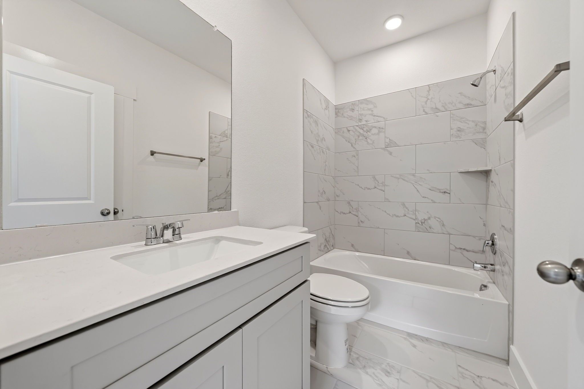 Modern white bathroom with marble tile shower, tub, and vanity in Davidson Homes The Holly F plan, Josephine, Texas