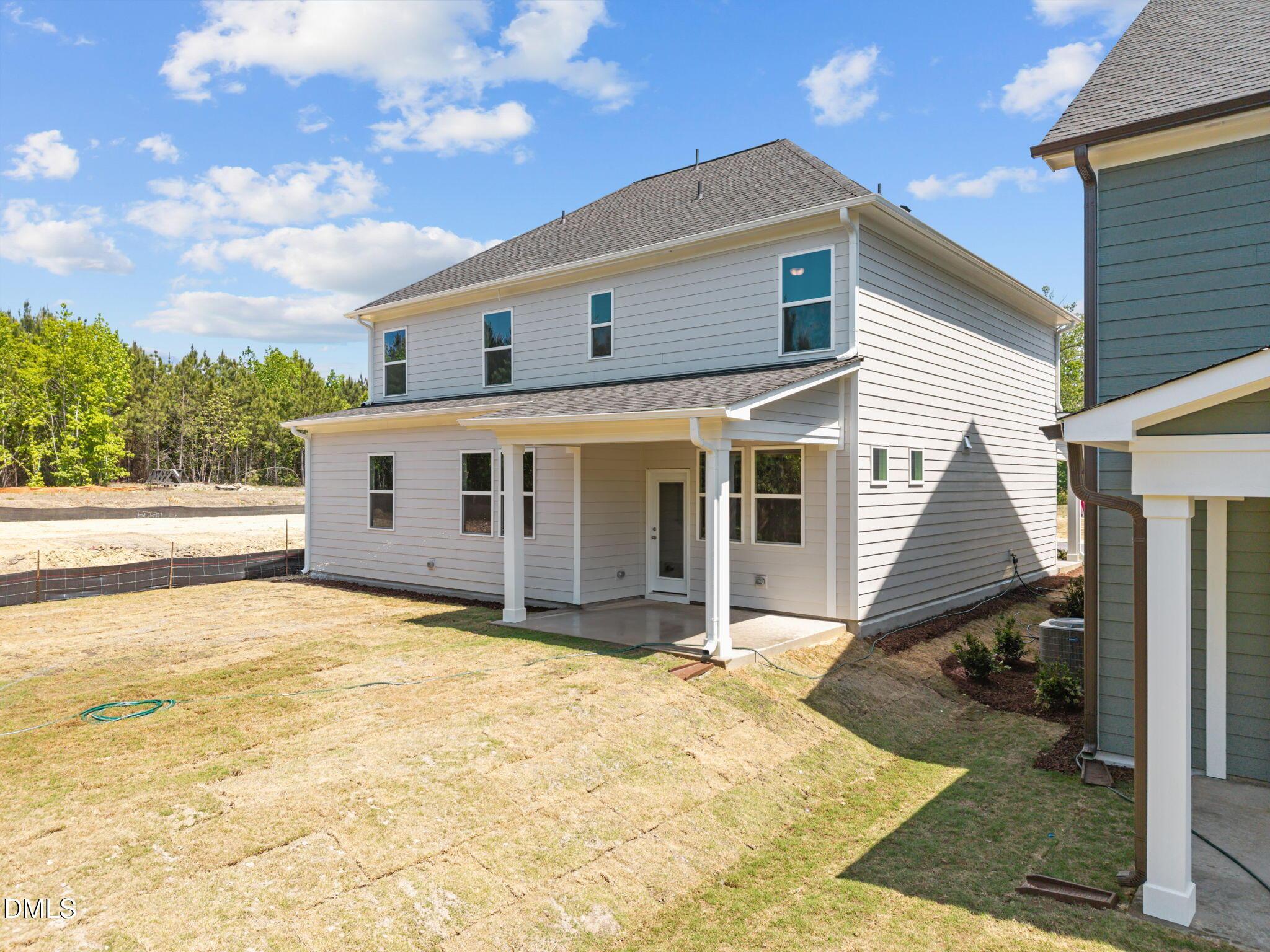 Rear view of The Willow D 4-bedroom home with covered patio, windows, and landscaped backyard in Wendell Ridge, North Carolina by Davidson Homes