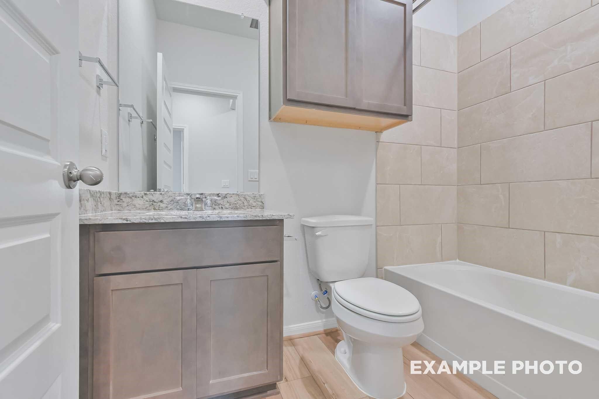 Elegant guest bathroom with soaking tub, single vanity, and subway tile walls in Davidson Homes The Frio F, Conroe, Texas