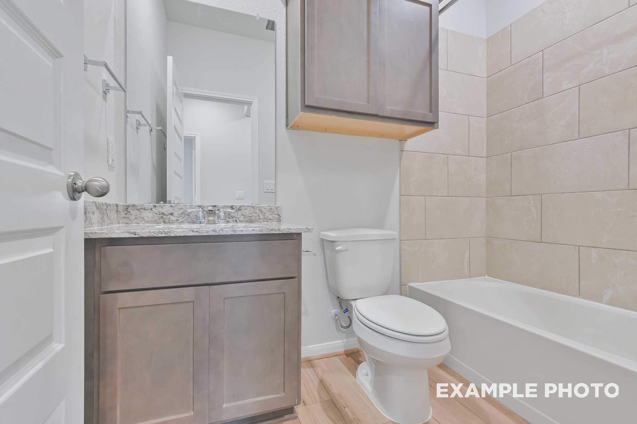 Elegant guest bathroom with soaking tub, single vanity, and subway tile walls in Davidson Homes The Frio F, Conroe, Texas