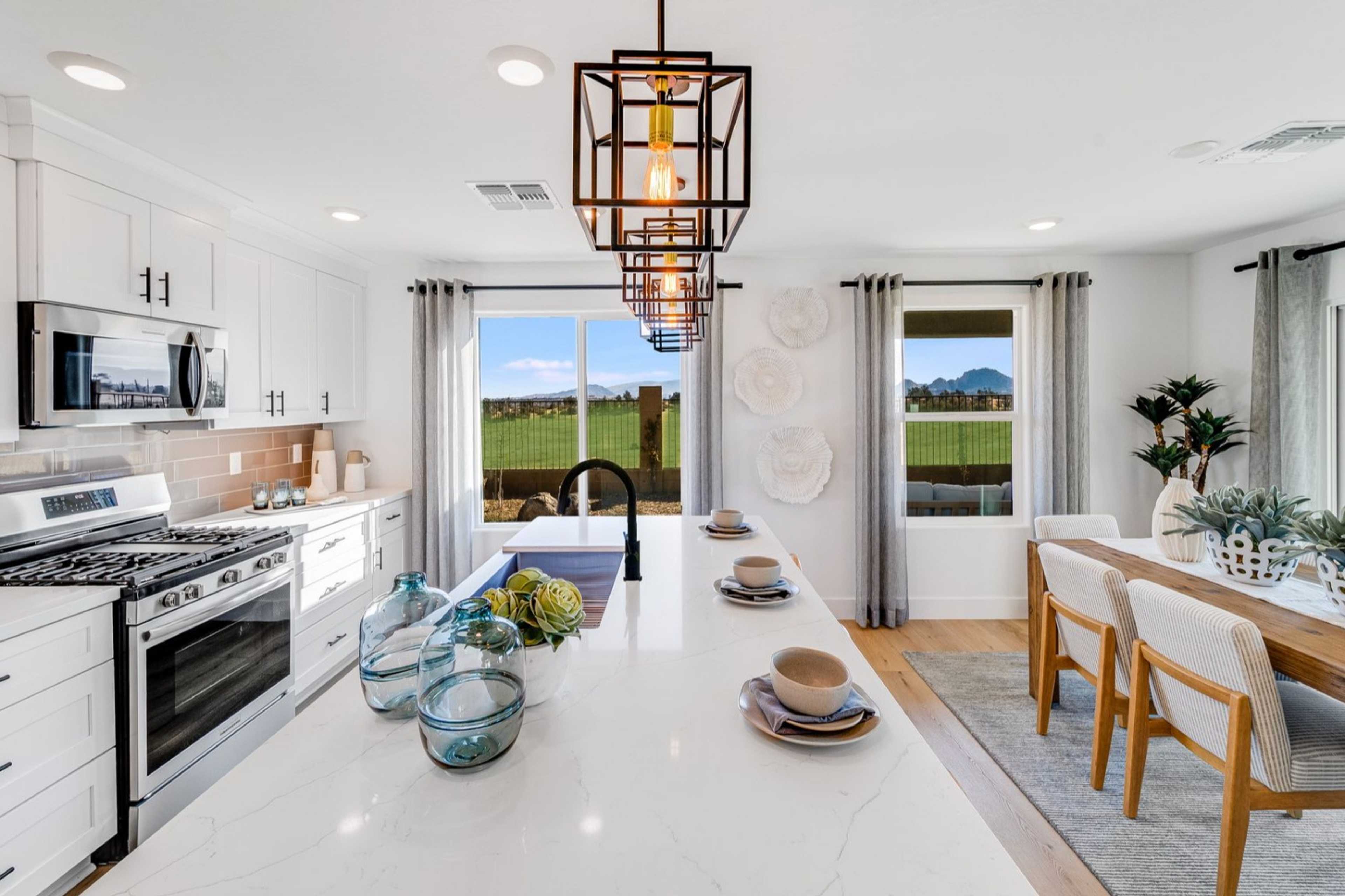 Modern kitchen in The Wilmington B featuring white island sink, stainless appliances, pendant light, and dining nook with Prescott AZ views