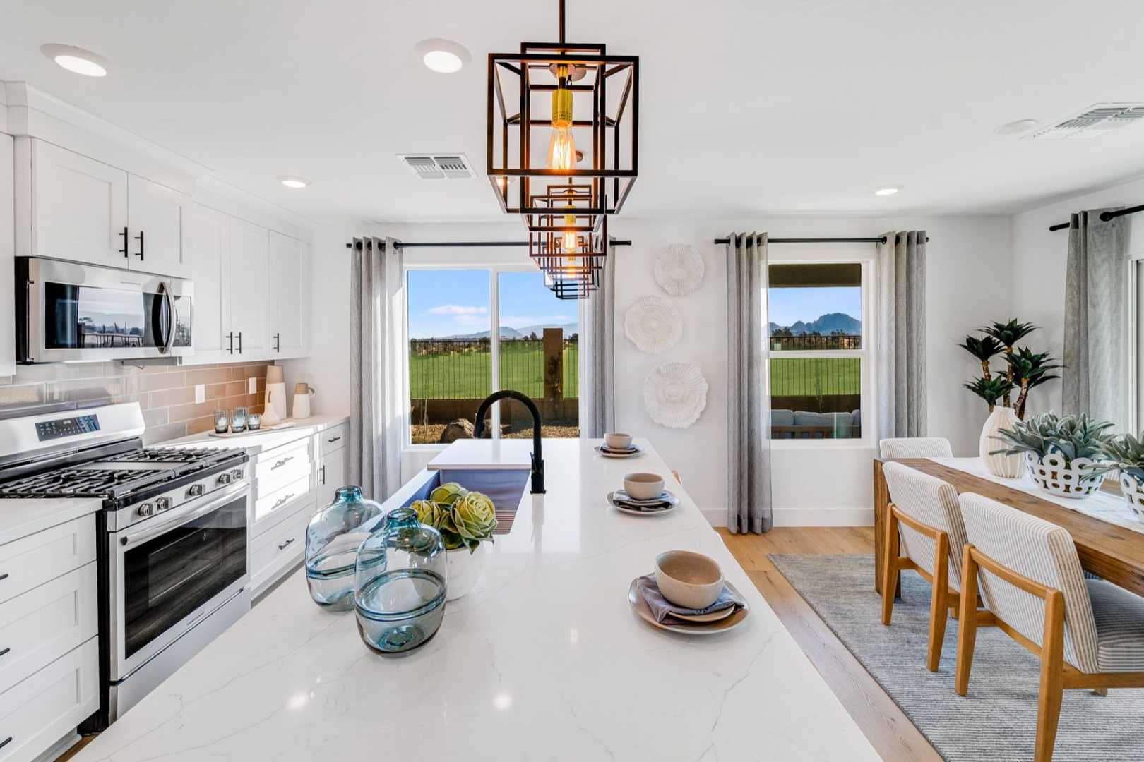 Spacious Wilmington kitchen featuring white cabinetry, large quartz island with farmhouse sink, and dining nook with desert view