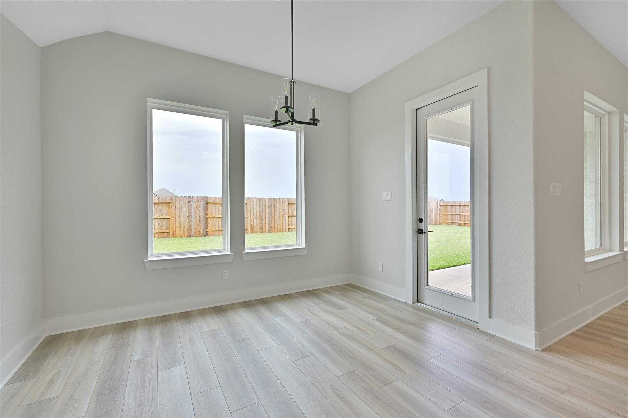 Bright dining room with chandelier, large windows, and French doors to fenced backyard in Davidson Homes The Edward C, Lago Mar, Texas City