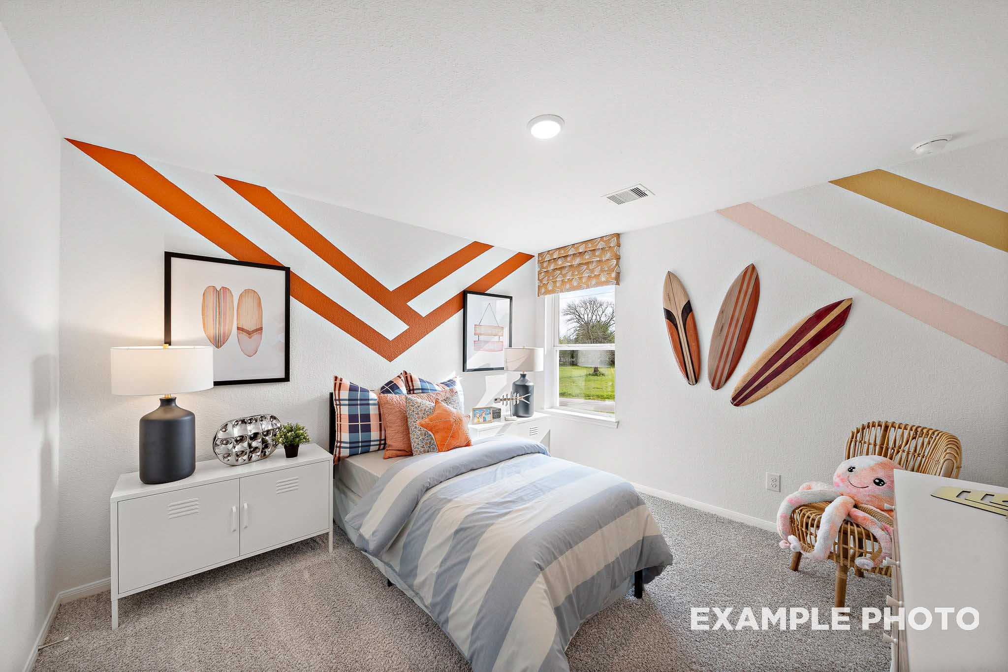 Cozy surf-themed children's bedroom in The Sabine with zigzag orange walls, surfboard decor, twin bed, and rattan chair
