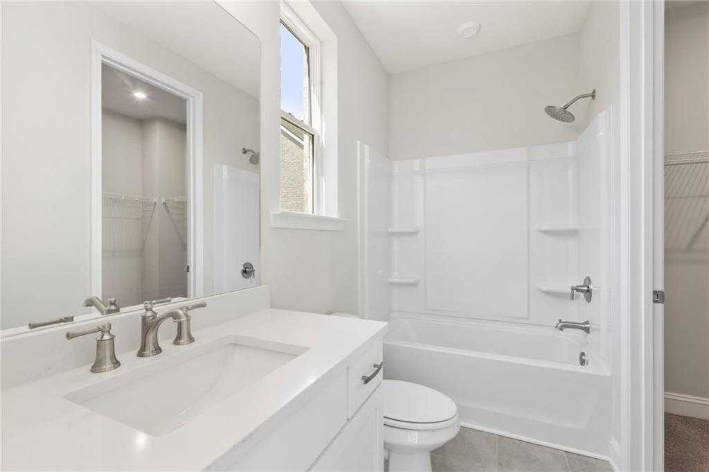 Modern secondary bathroom with dual sinks, soaking tub, glass shower, and walk-in closet in The Danbury C, Buford, Georgia