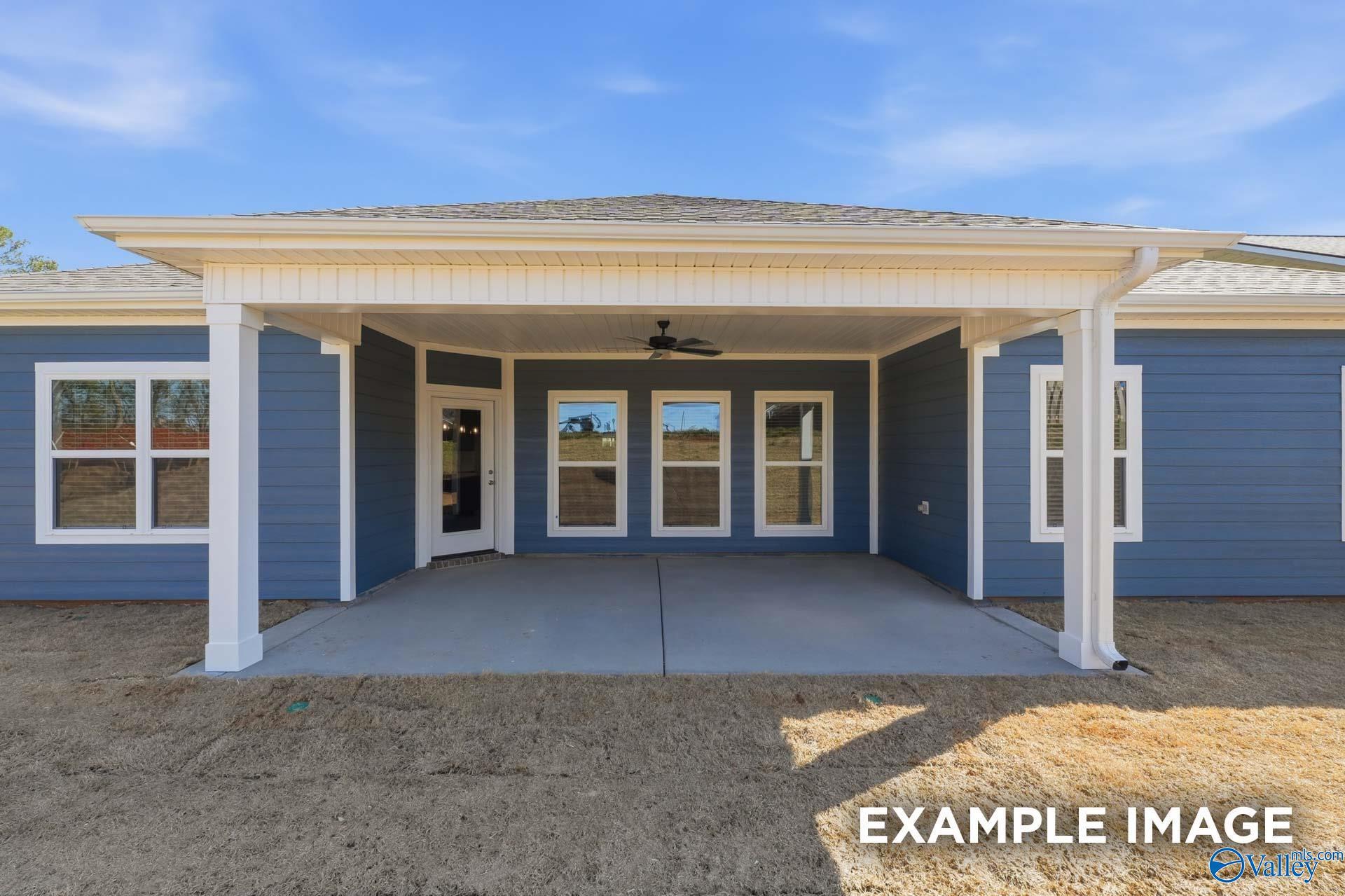 Covered patio with ceiling fan and large windows on blue-sided Davidson Homes The Harrison C in Evergreen Mill, Madison, Alabama