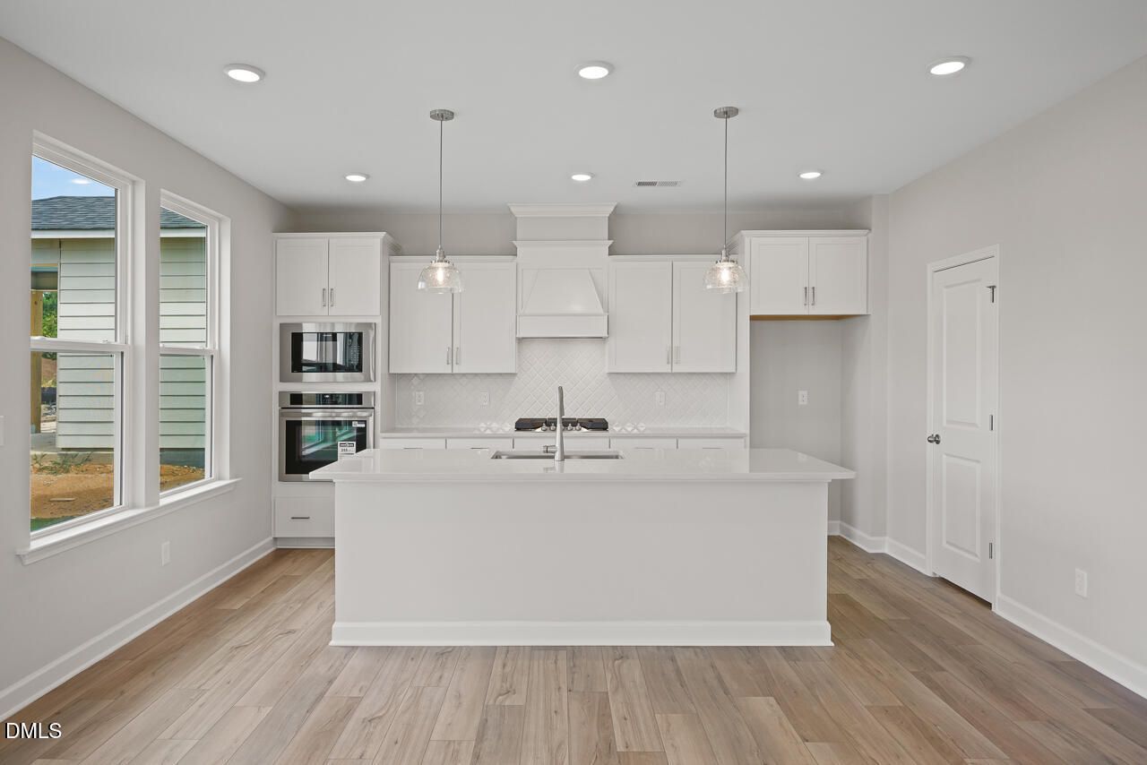 Modern white kitchen with island, stainless appliances, and quartz countertops in The Chestnut floor plan, Wendell Ridge.