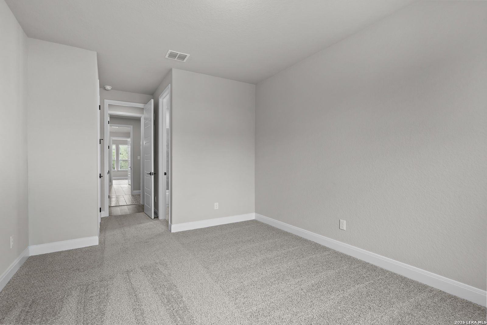 Spacious secondary bedroom with gray carpet and neutral walls in Davidson Homes The Belmont H, Castroville, Texas