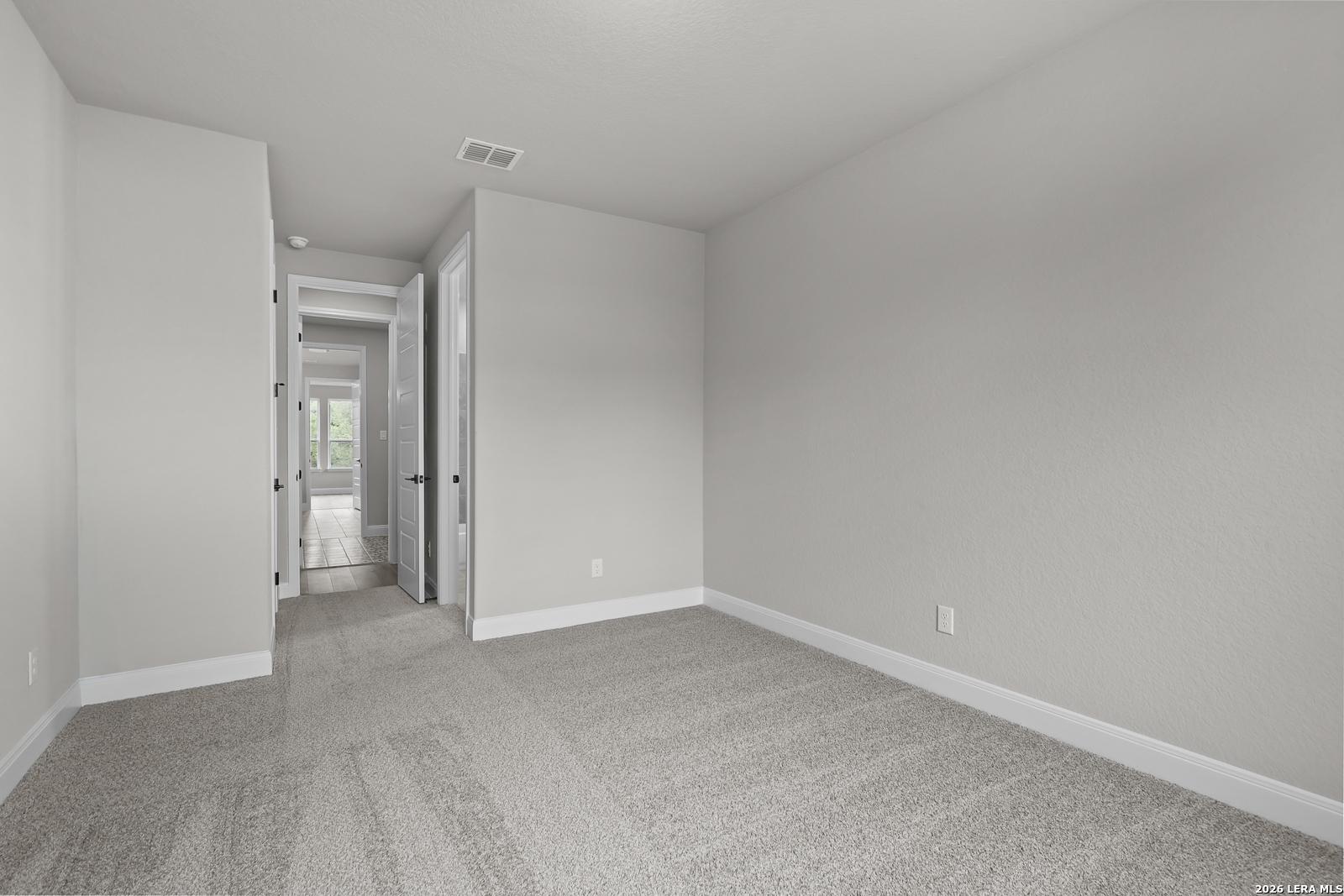 Spacious secondary bedroom with gray carpet and neutral walls in Davidson Homes The Belmont H, Castroville, Texas