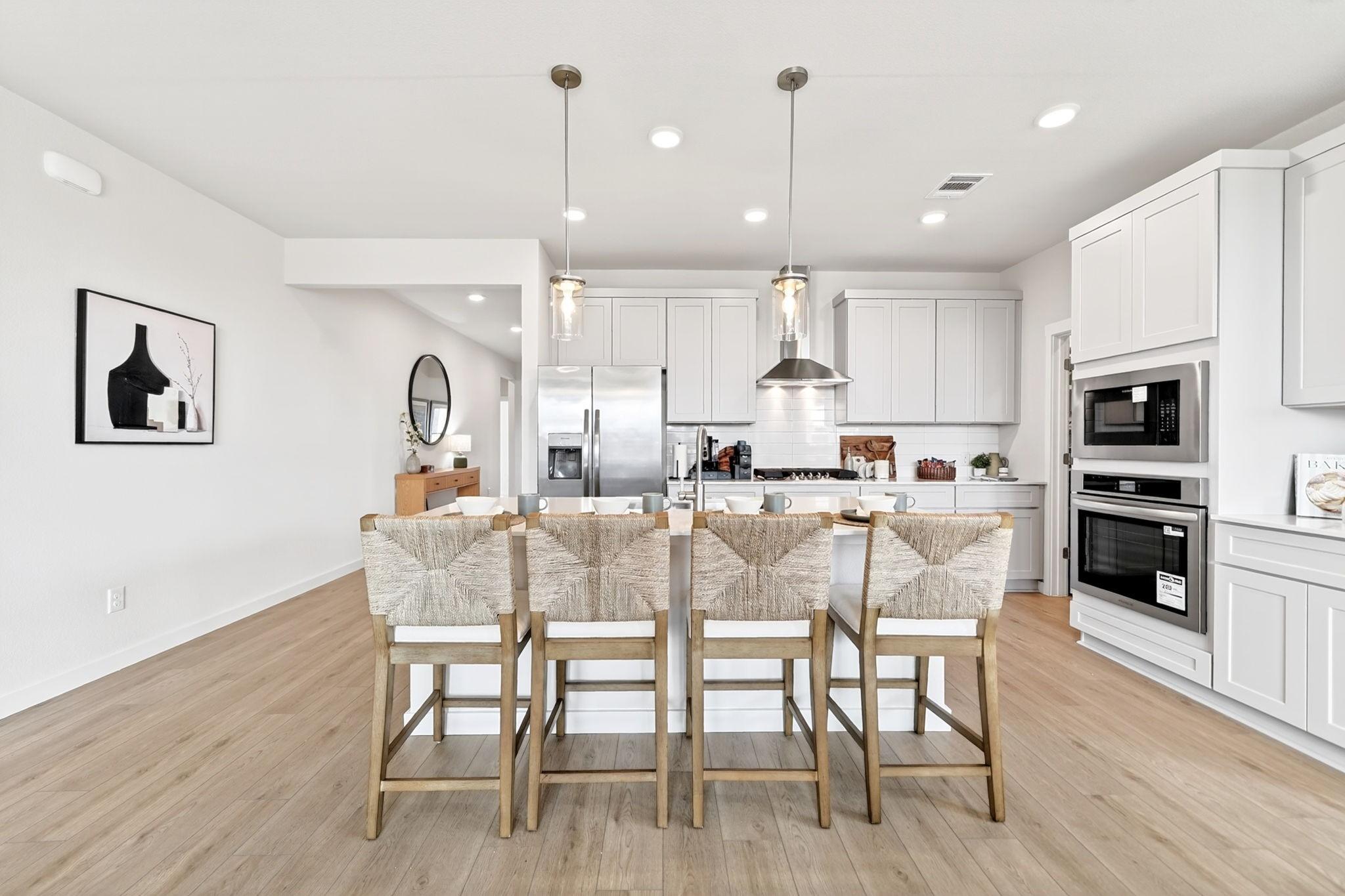 Modern kitchen with designer island, pendant lights, and stainless steel appliances in The Laurel M floor plan, Anna, TX.