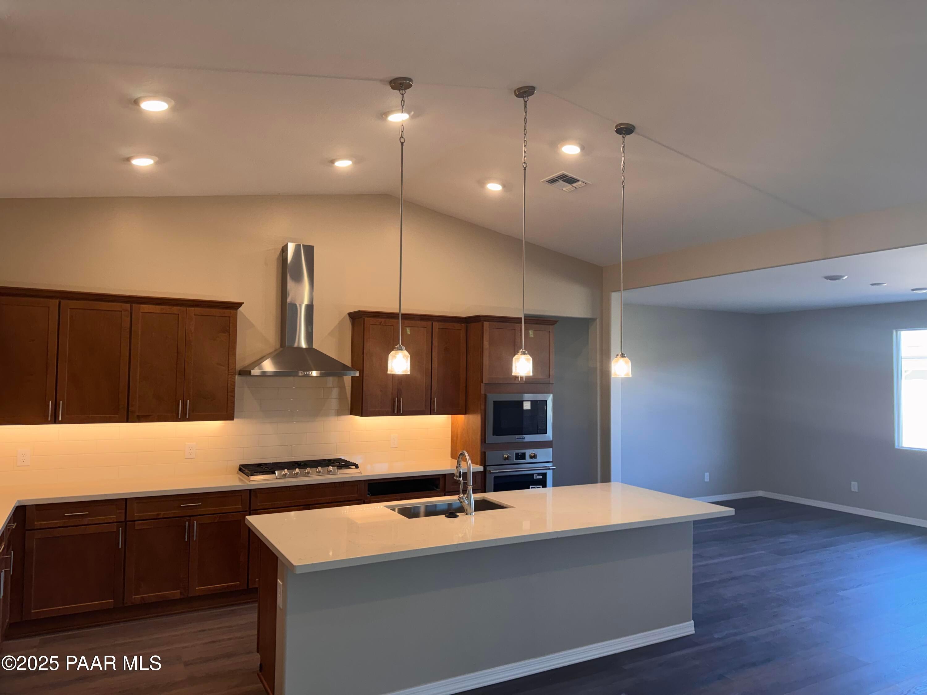 Modern kitchen with quartz island, espresso cabinets, stainless appliances, pendant lights in The Sunrise II A, Prescott AZ