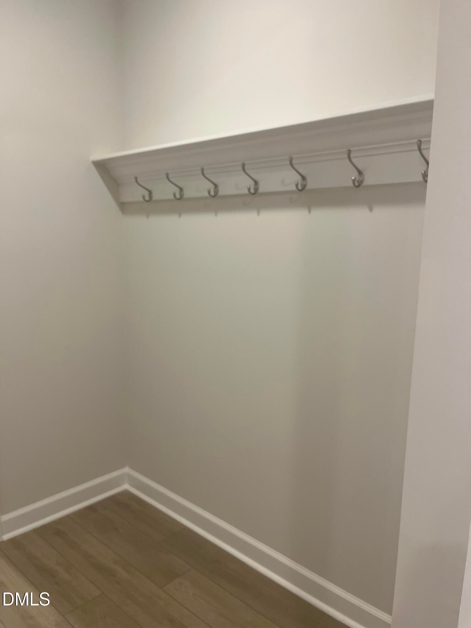 White wooden shelf with metal hooks in organized entry closet, hardwood floors in Davidson Homes Ashport G, Wake Forest NC