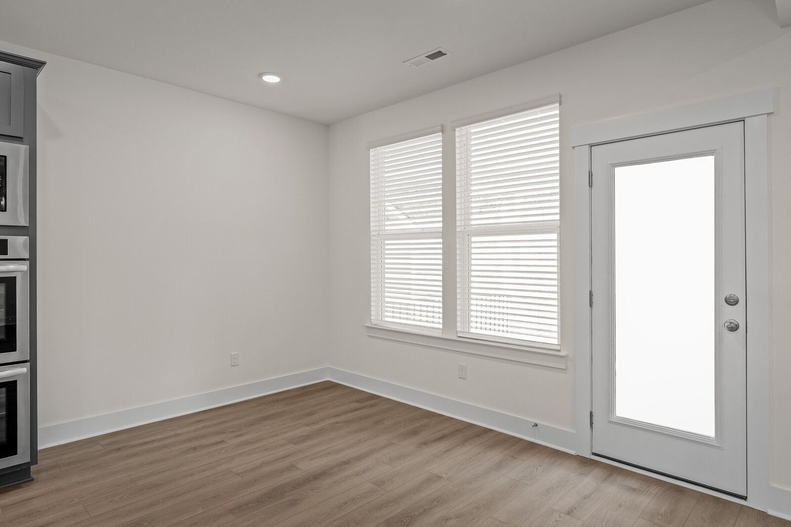 Bright breakfast nook with wood-style flooring and backyard access in The Willow floor plan at Woods Crossing, Gallatin.