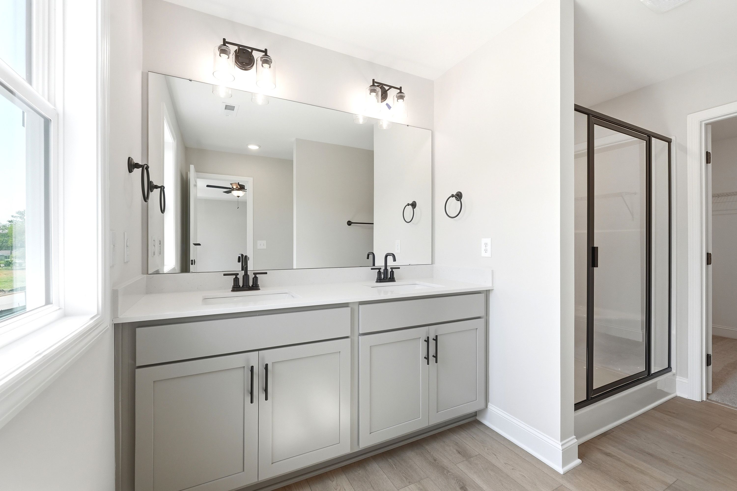 Modern master bathroom in The Russell A featuring a double vanity, grey cabinetry, and a walk-in shower.